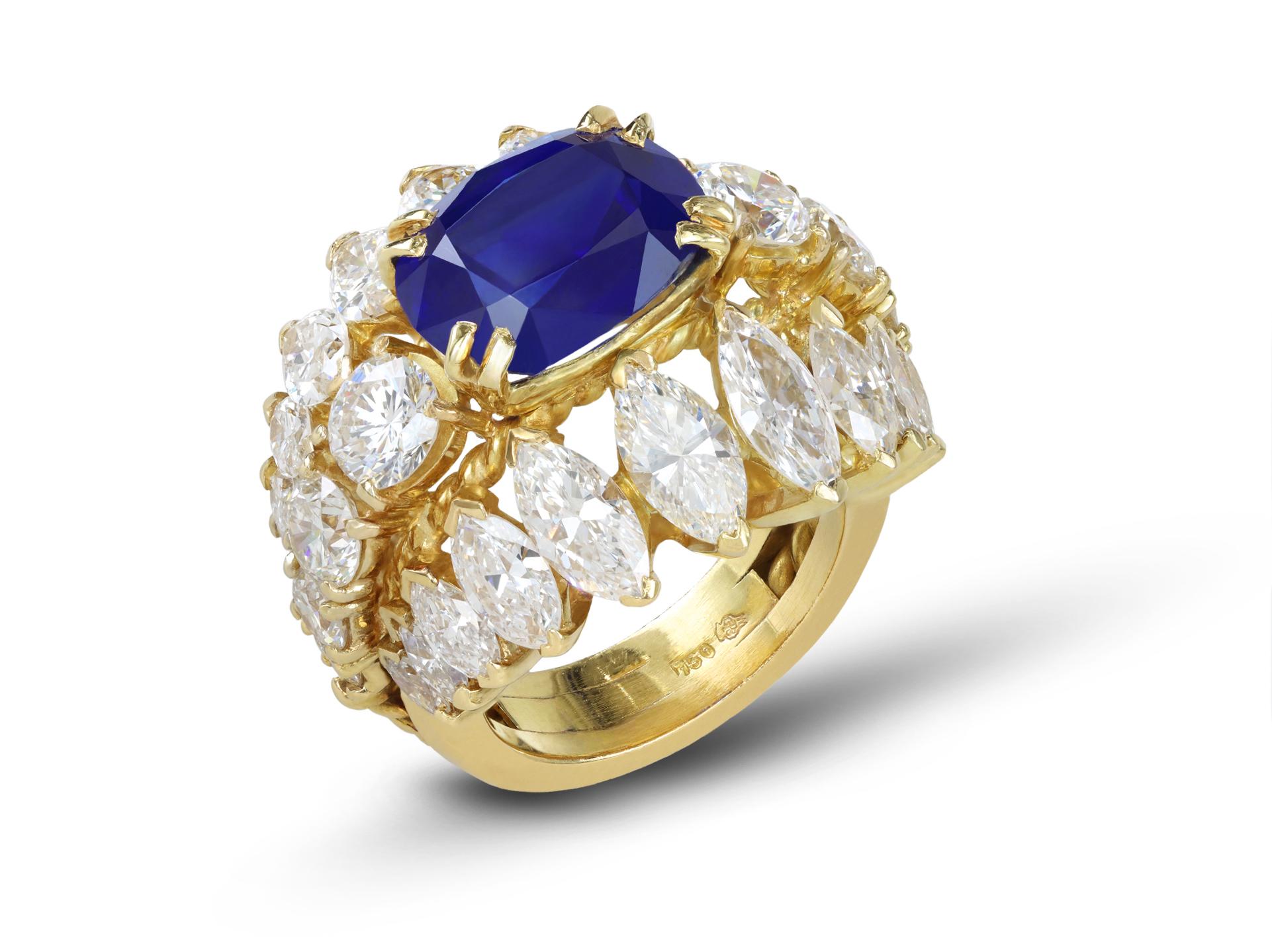 Burmese sapphire and diamond cluster ring. Set centrally with one cushion shape old cut natural unenhanced Burmese sapphire in an open back claw setting with an approximate weight of 5.36 carats, flanked by eight round brilliant cut diamonds in open