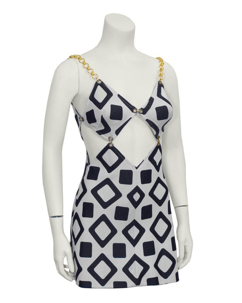 Flirty Versace-esque black and white cut-out minidress from the 1960's. Features geometric pattern with diamond shape cutouts around waist. Chain-link straps and chain detail on bra. Perfect as bathing suit cover-up. Back zip closure. Excellent