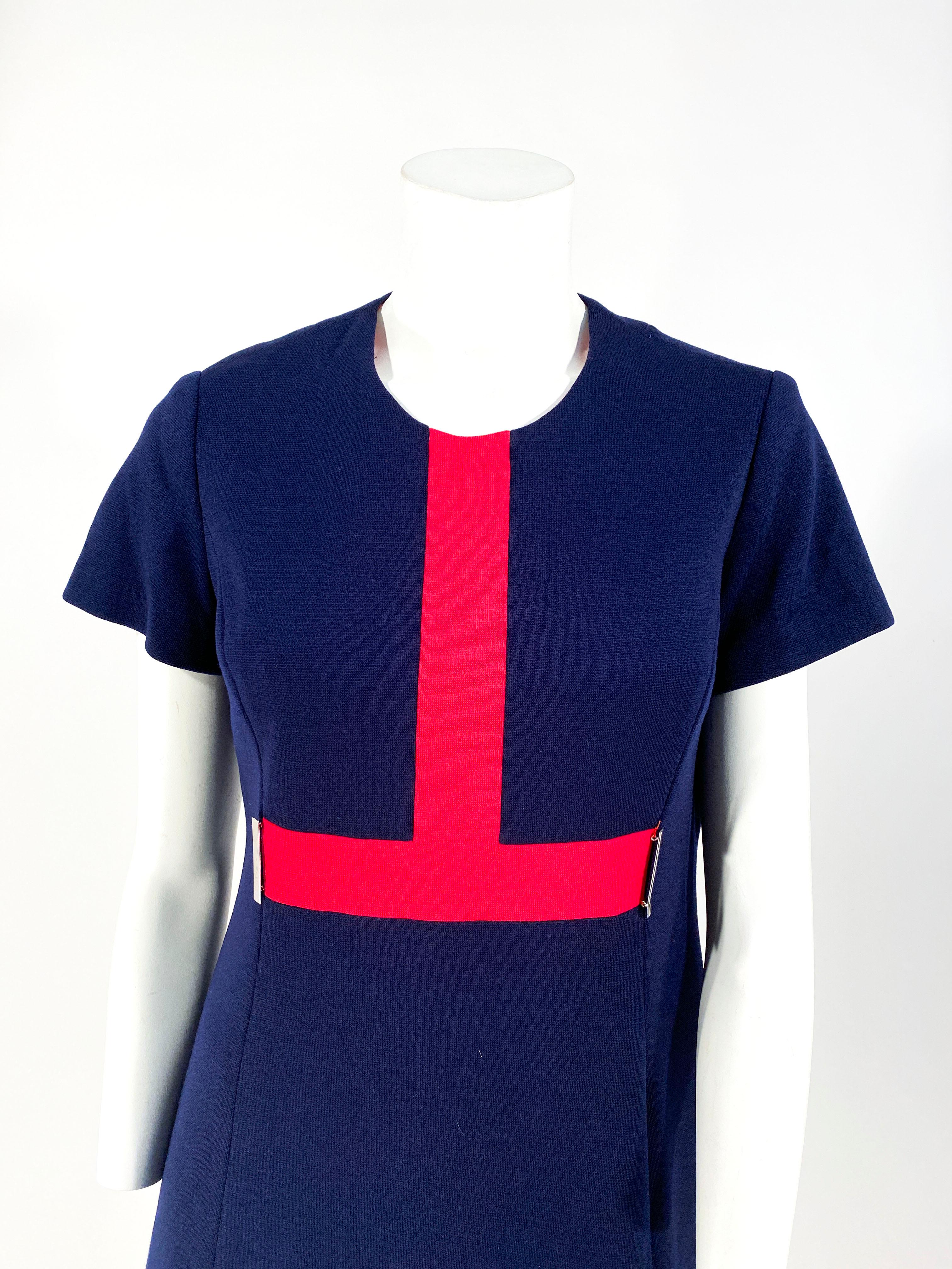 1960s navy blue knit wool mod a-line dress with  short sleeves, a bold red decorative in-set trim, round collar, and metal brass finishing. The back of the dress has a zipper closure and the interior is lined with red satin. 