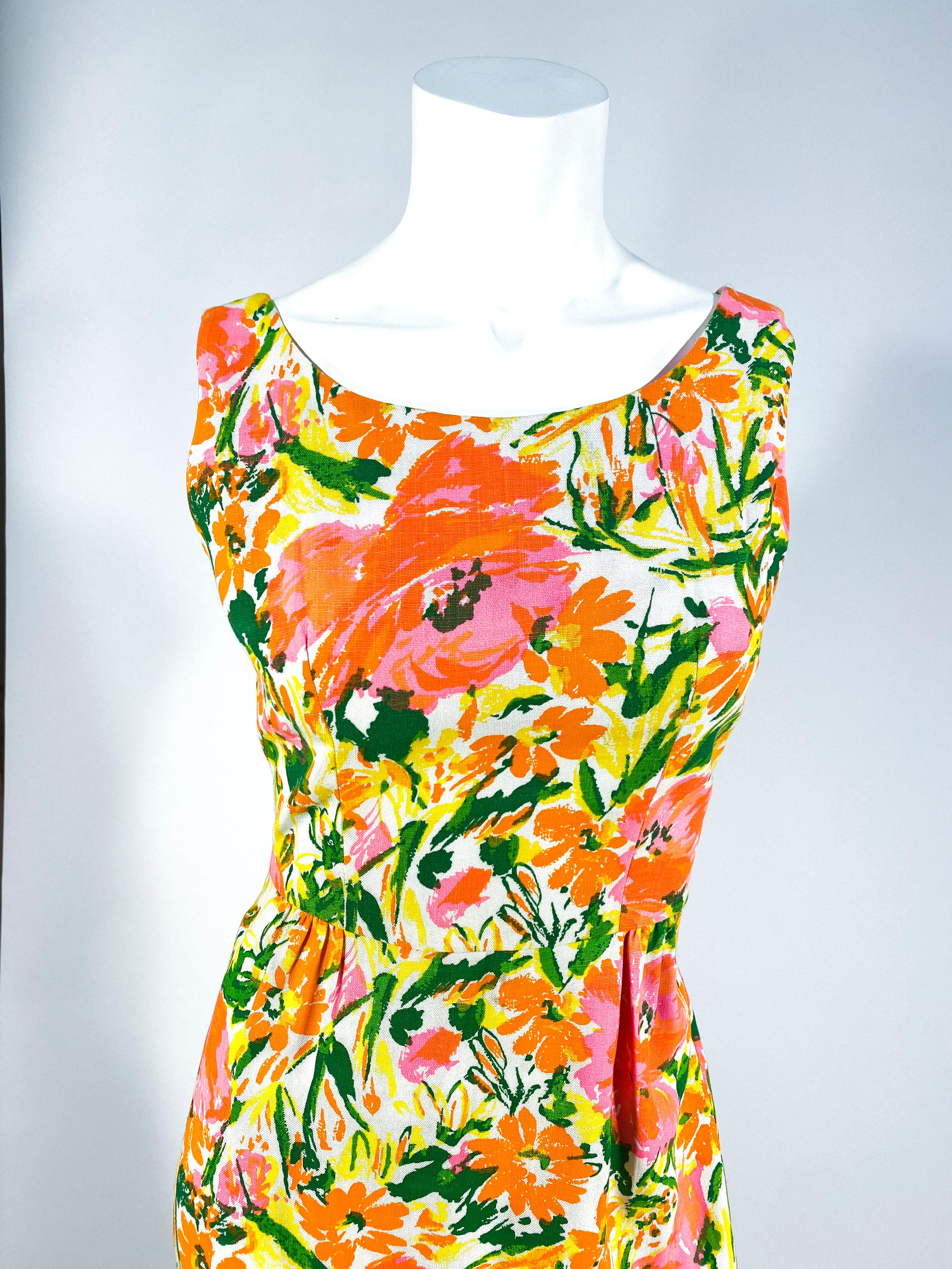 Baumwoll-Tageskleid aus den frühen 1960er Jahren mit abstraktem Neonblumenmuster. Das Mieder läuft in der Taille spitz zu, die mit dem mäßig gefalteten Rock verbunden ist und so eine schöne Silhouette ergibt. Dieses Stück ist ungefüttert und wird