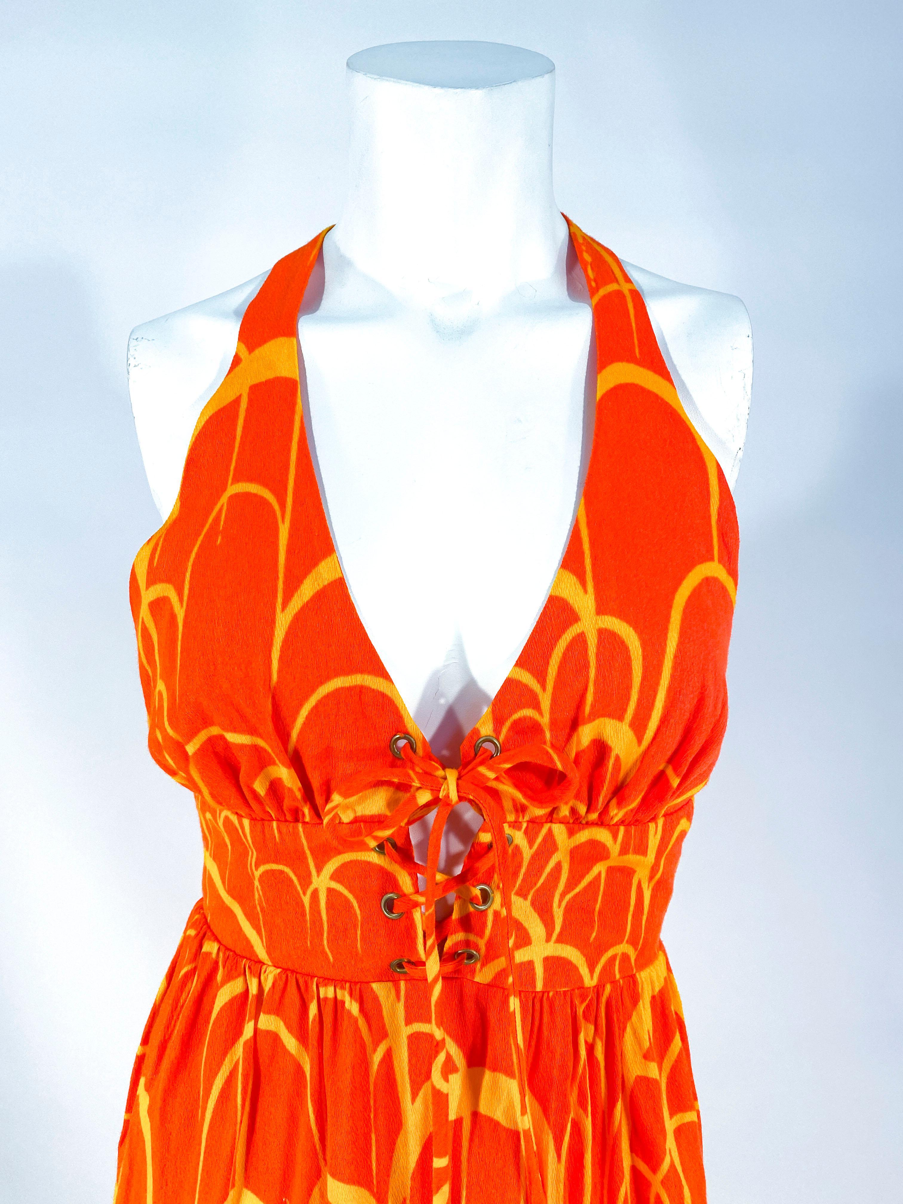1960s neon orange and gold printed acrylic backless summer dress with in-set cummerbund was it, gathered halter bust with draw sting closure, and a lace up bodice enforced with metal eyelets. The back has a short back zipper closure. 