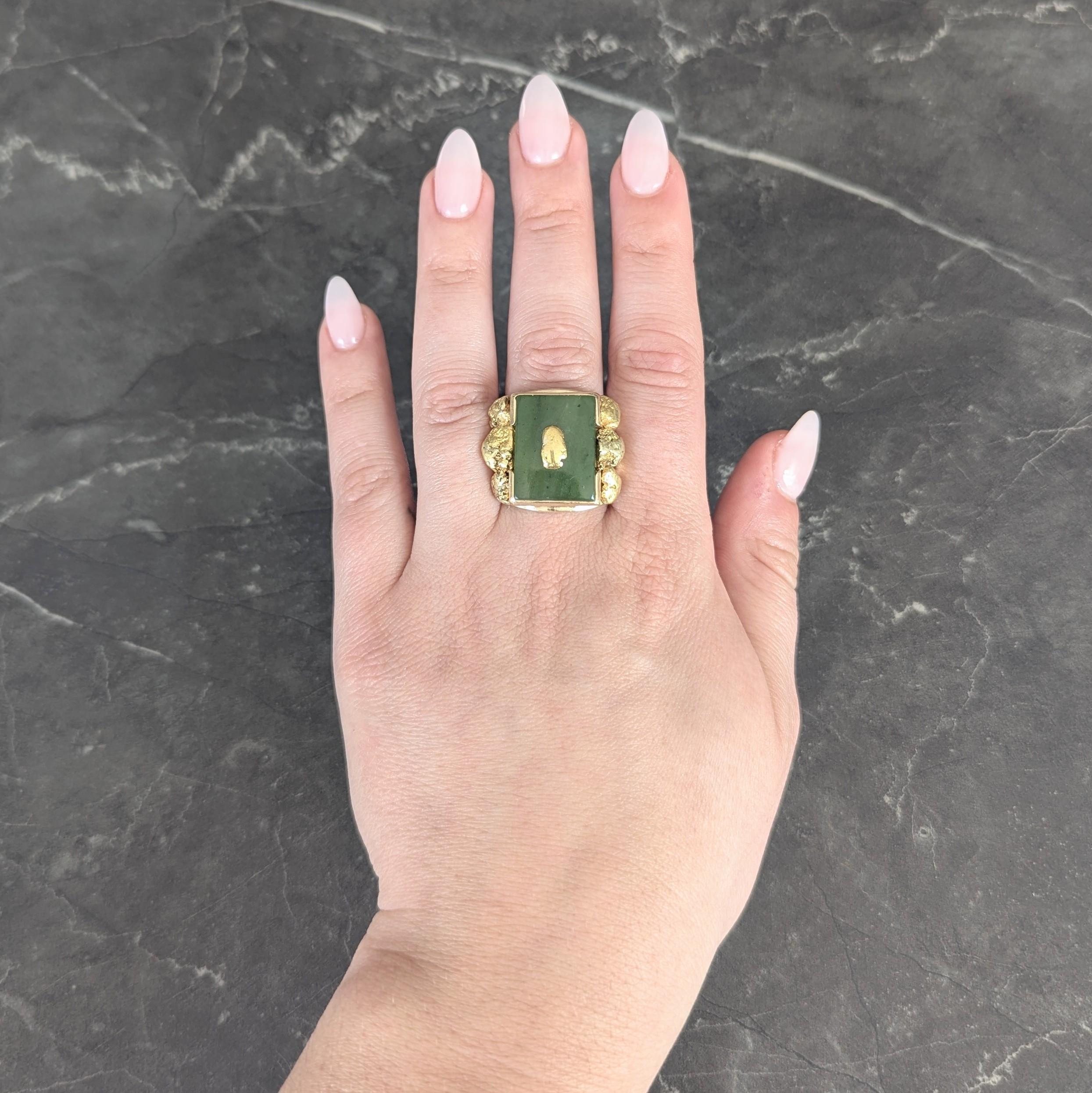 Al centro una tavoletta di giada nefrite di forma rettangolare di 14,5 x 18,5 mm.
Verde muschiato semitrasparente con sottili maculature moderate e scure.
Incastonato in un semi castone e centrato da un'applicazione di pepite d'oro
Fiancheggiato da