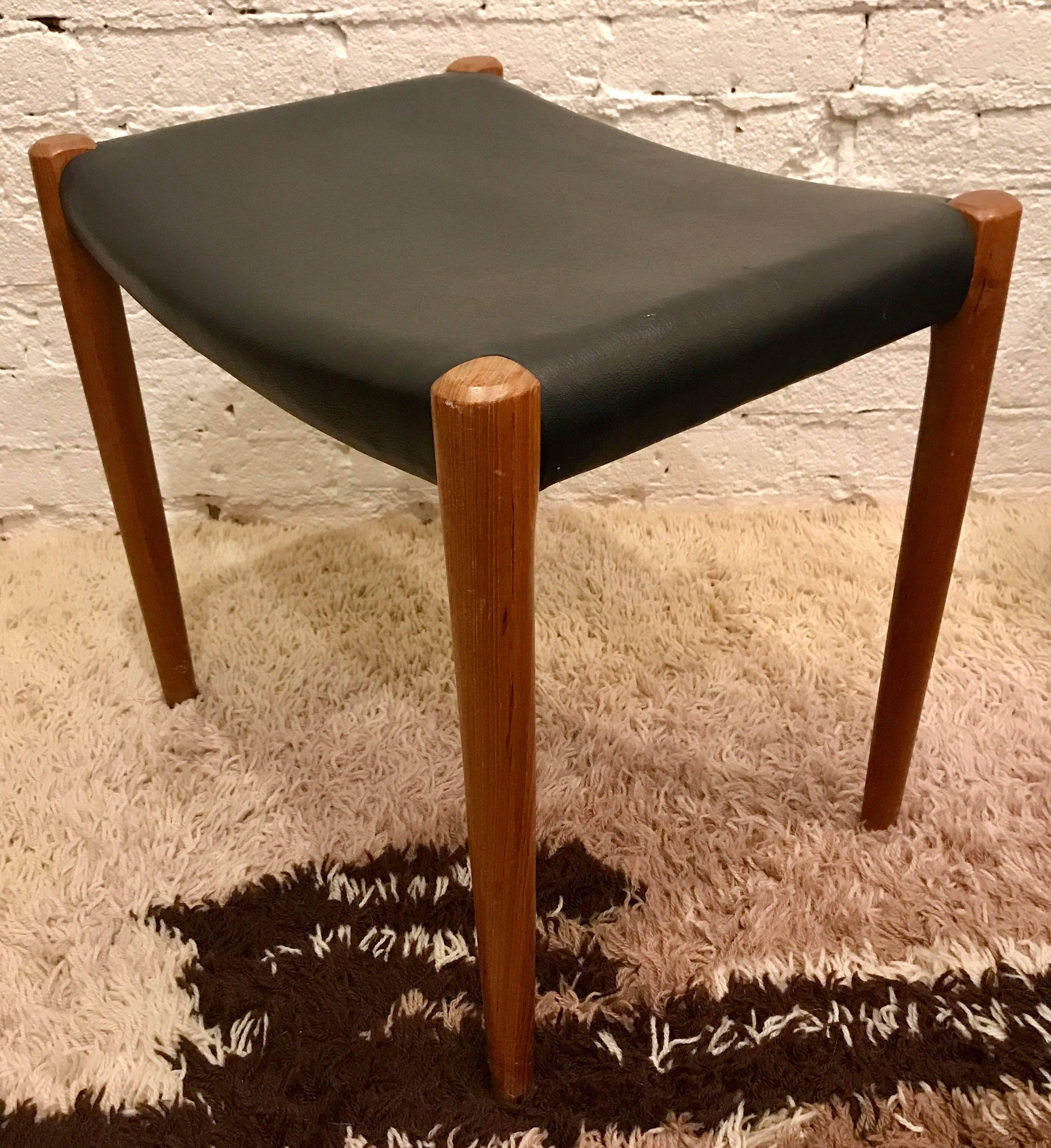 1960s Danish modern Model 80 teak footstool designed by Niels Moller for J.L. Moller. Footstool is upholstered in original black vinyl and marked with the Danish control stamp and the J.L. Moller logo.