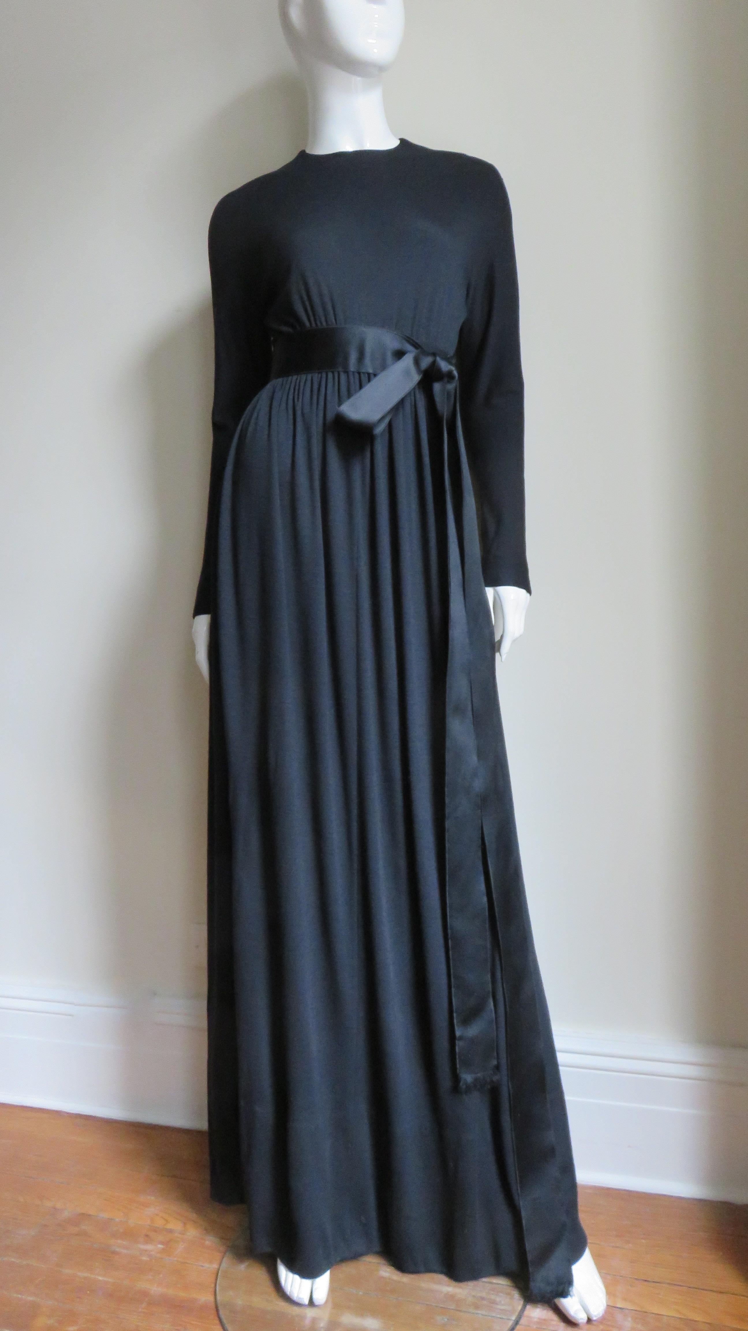 A gorgeous fine black wool jersey maxi dress gown by master designer Norman Norell.  It has a crew neckline, dolman sleeves with zipper wrists and a silk satin ribbon belt adorning the high waist onto which a fuller skirt is gathered.  It still has