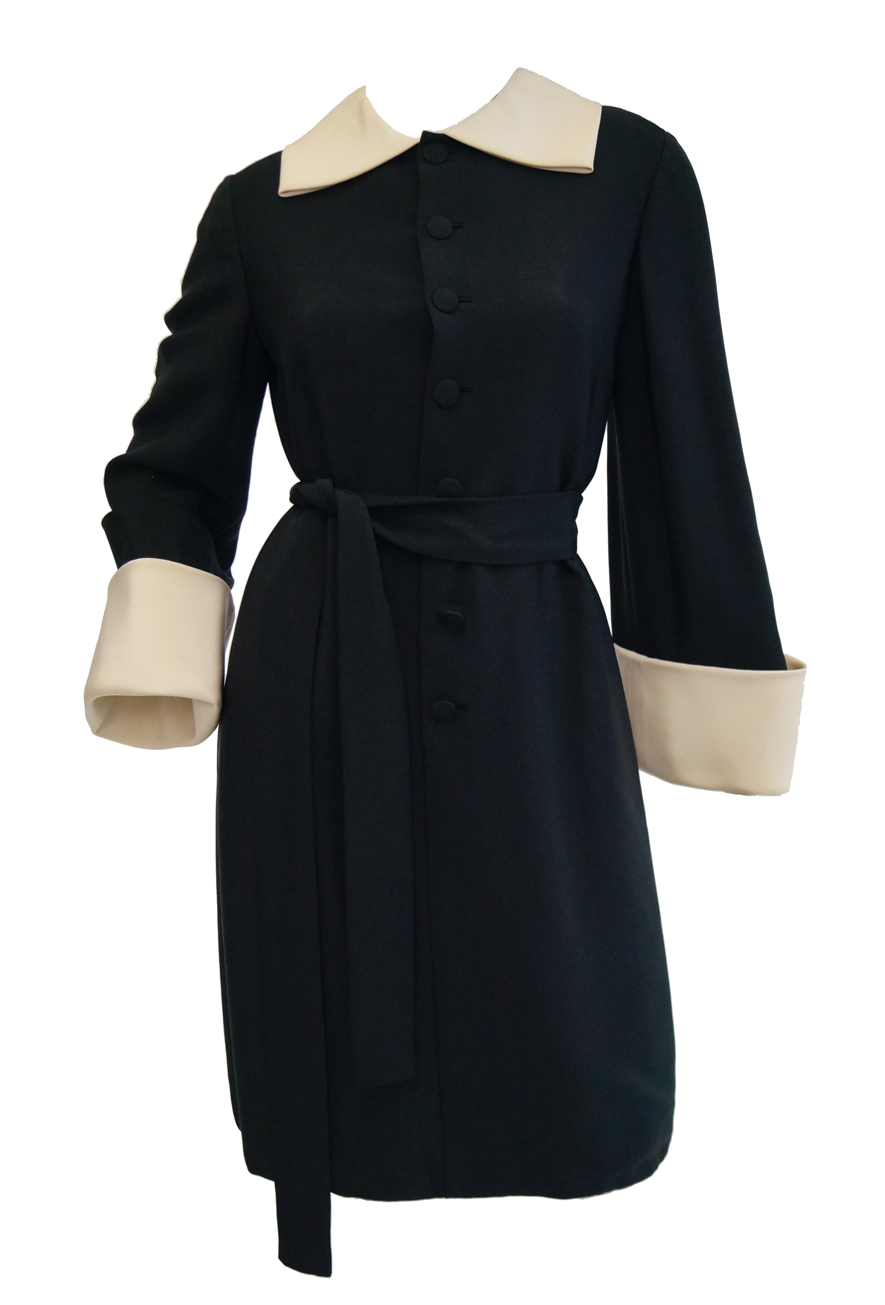 
Spectacular shift dress by Norman Norell!  The drama of this dress makes one feel as though it is a coat, with its large cuffed sleeves and large collar. The fabric is black silk with a nice hand. It also has a belt to cinch in the waist. It is a
