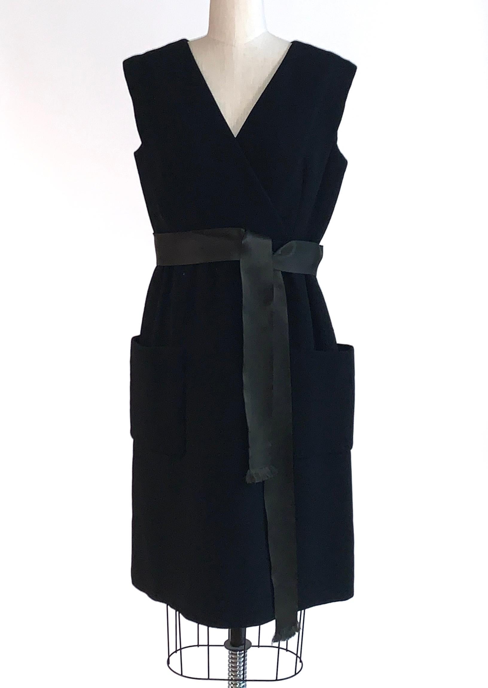 Vintage Norman Norell 1960s sleeveless little black dress with patch pockets at sides and ribbon sash at waist. crossover v neck detail at bust, and buttons up back of dress from middle. Keystone dress shields at inner underarms. 

Labelled Norman