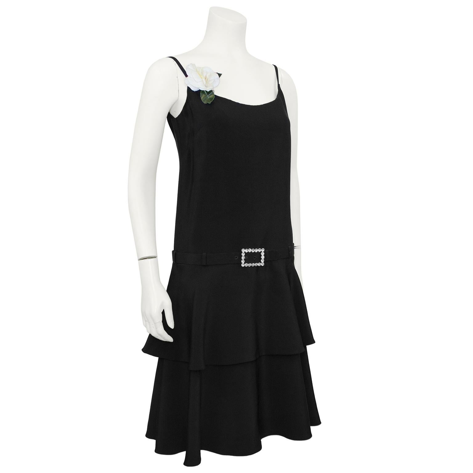Norman Norell black silk drop waist dress with rhinestone buckle belt and tiered skirt from the 1960's. Attached gardenia accent on the strap may not be original, but so pretty. Pulls on over the head, the belt can be unfastened.  For a modern take