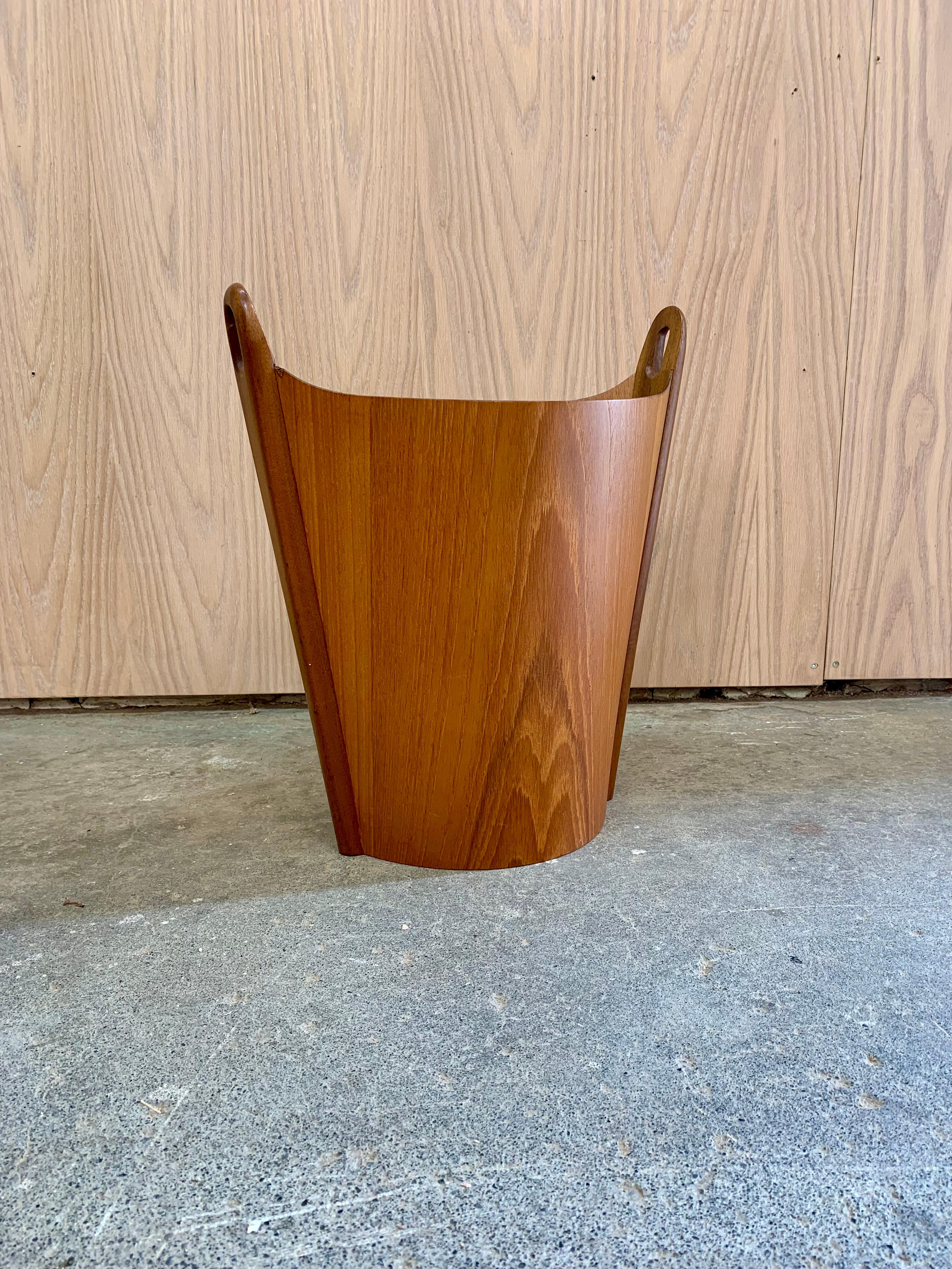 Design/One pour P.S. Fabriquée en Norvège dans les années 1960, cette corbeille à papier sculpturale en teck est un brillant exemple du design scandinave dans ce qu'il a de plus élégant et de plus fonctionnel. Fabriqué en placage de teck richement