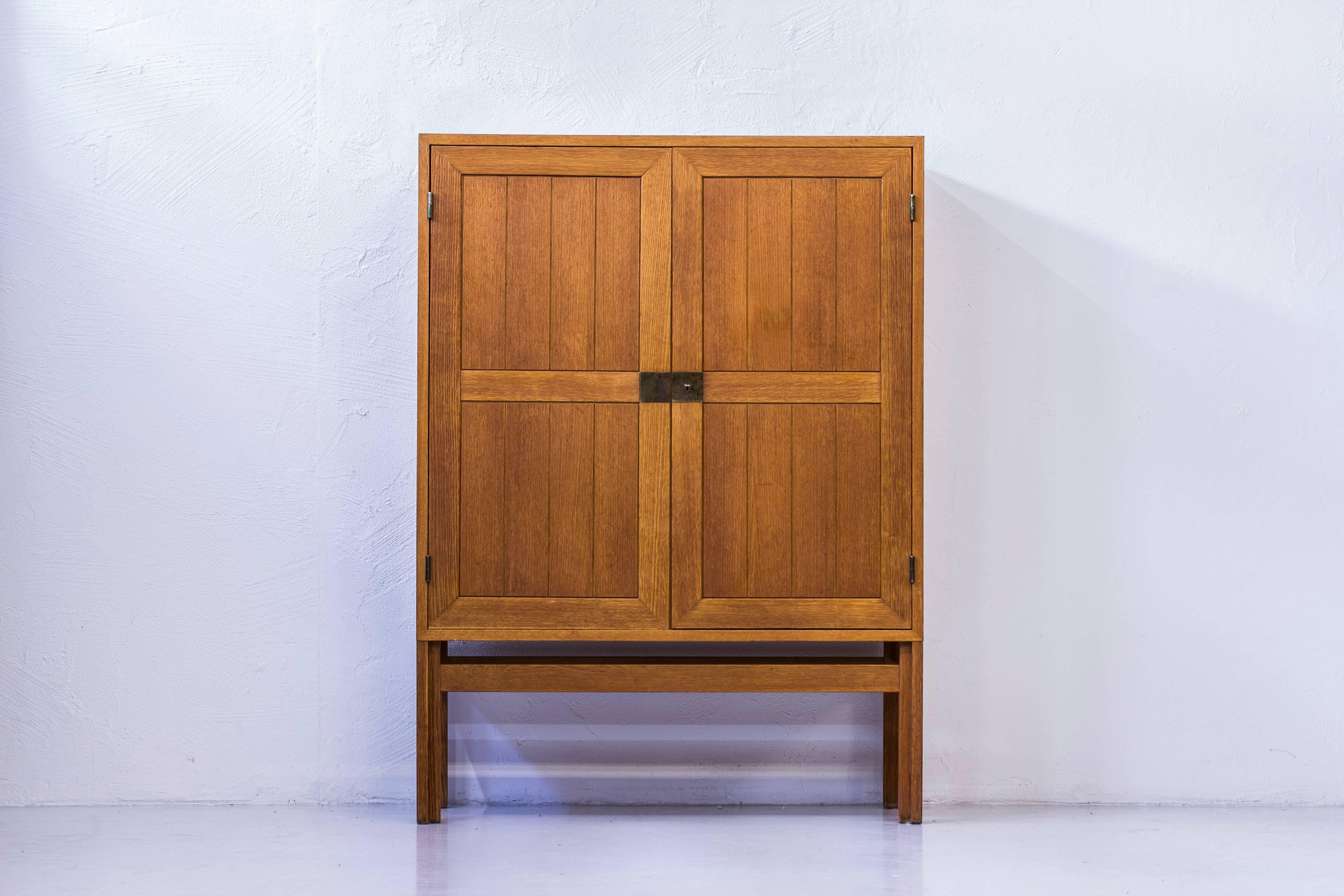 Cabinet designed by Kurt Østervig during the 1960s. Produced by Vamo furniture factory in Denmark. Made from oiled oak on the outside with brass hinges and details on doors. Oak inside with teak veneer on the inside of the doors. Three Adjustable