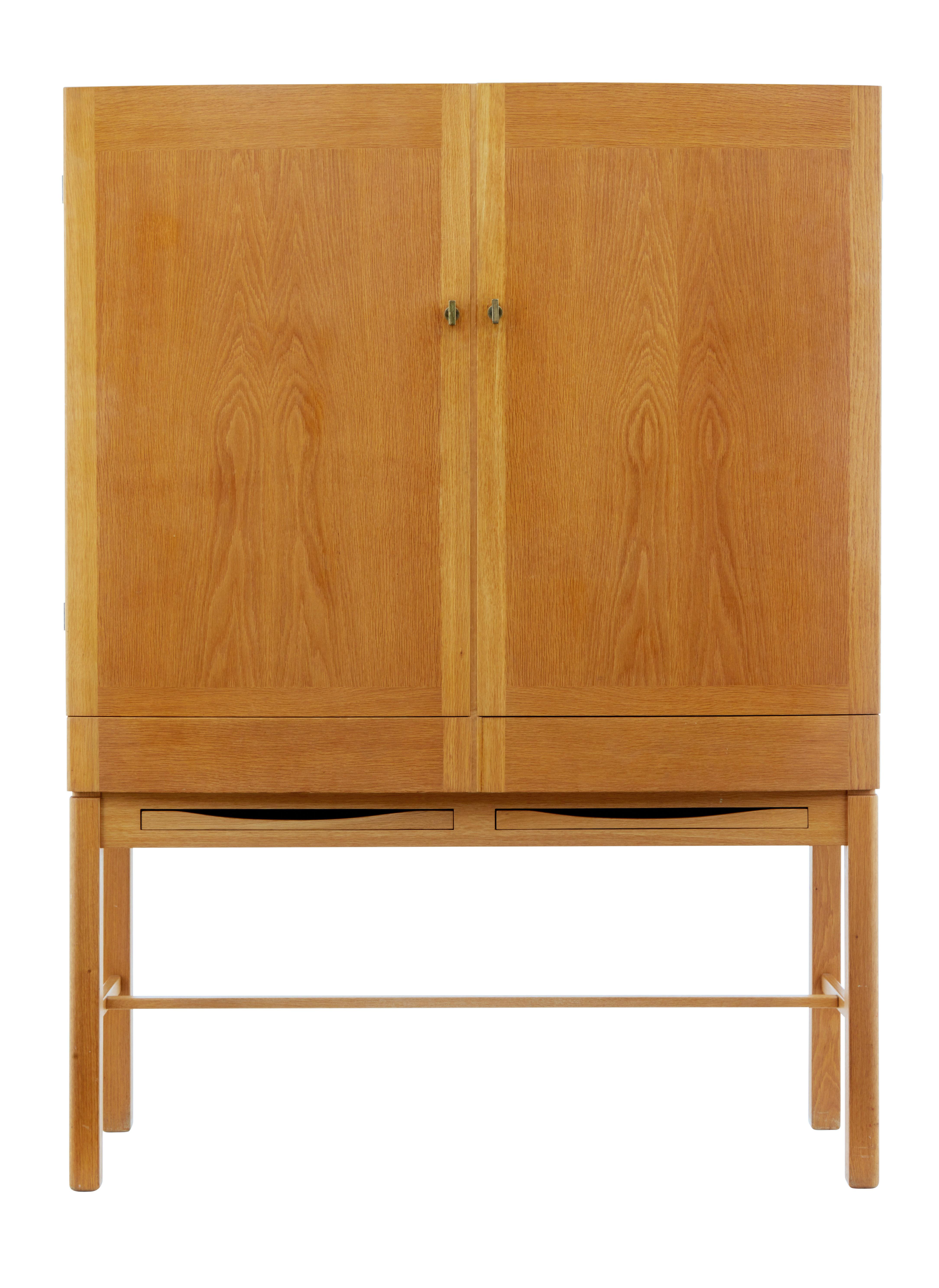 Fine quality Scandinavian cabinet designed by Gunnar Mystrand for Kallemo.

Oak double doors open to a partially fitted interior. Central partition with 2 shelves on either side and 2 drawers on the right hand side. Below the cabinet are a further