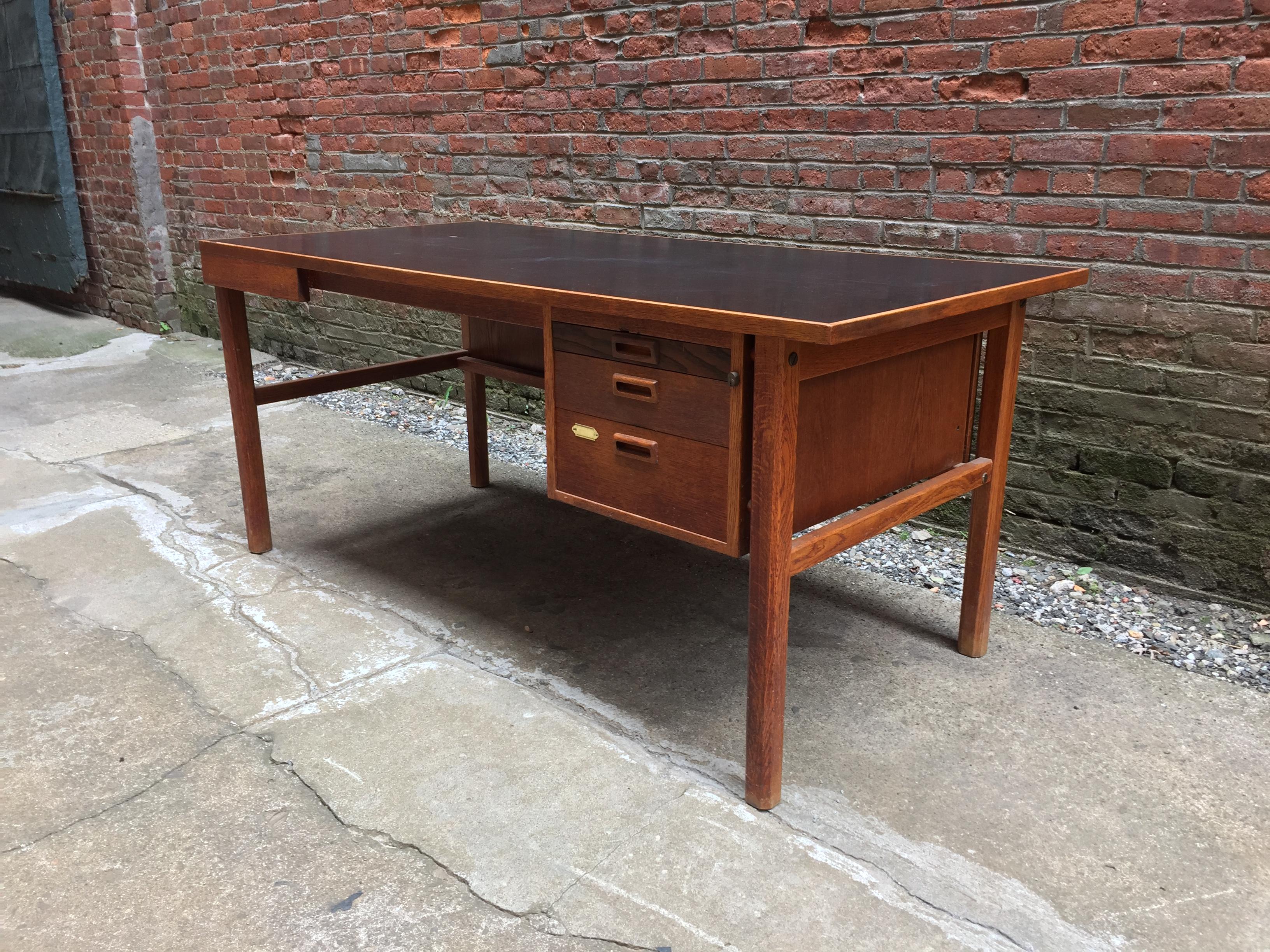 Solid oak frame with a black laminate top. Beautiful old growth tight grain. Three graduated drawers with many options due to the size of the flat surface, circa 1960. Original finish. Good condition with some minor light scratches on the black
