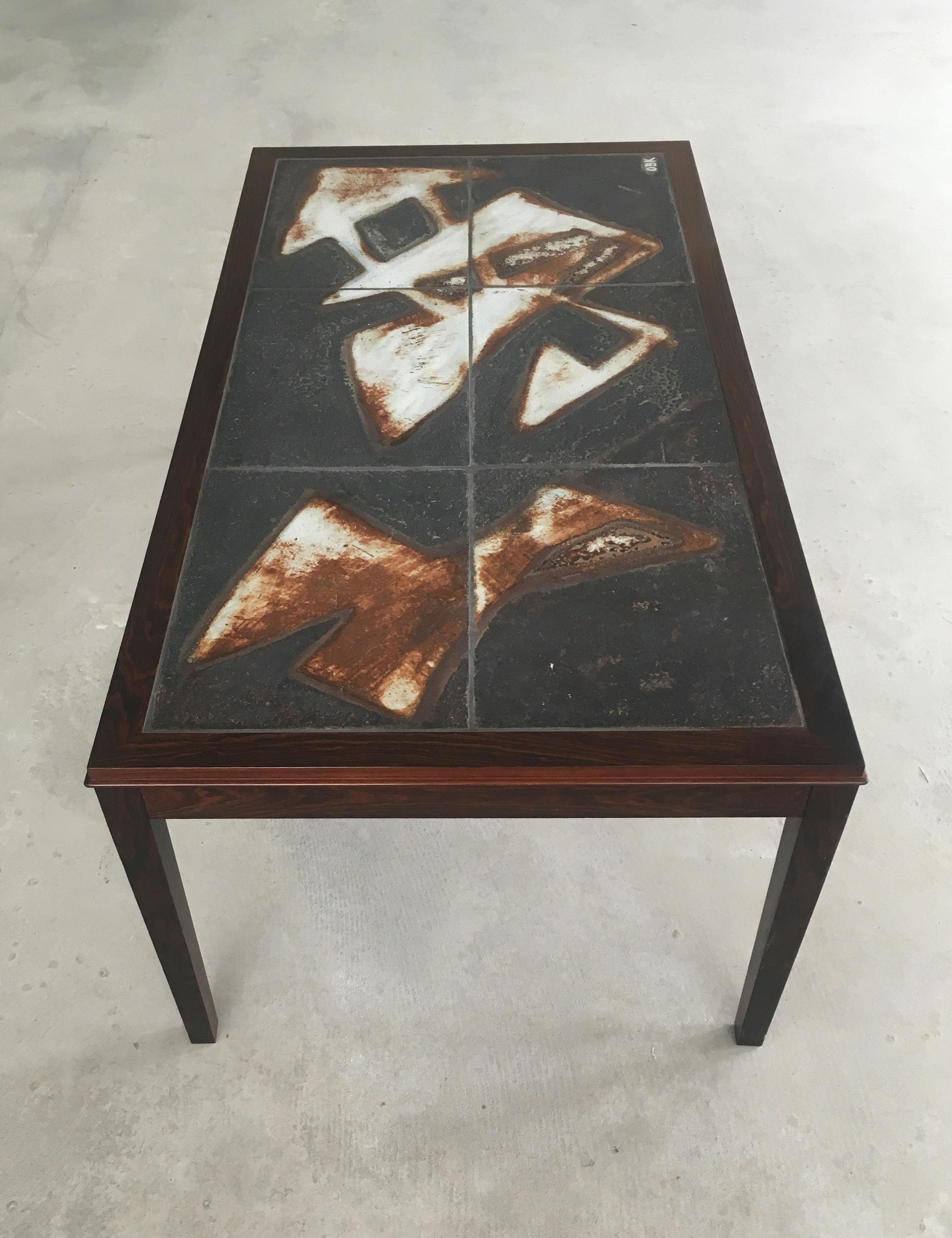 Tile topped coffee table in rosewood and abstract stoneware tile designed and signed by Danish artist Ole Bjørn Krüger.

The coffee table has been restored and refinished by our cabinermaker and is in very good condition.

We are shipping our pieces