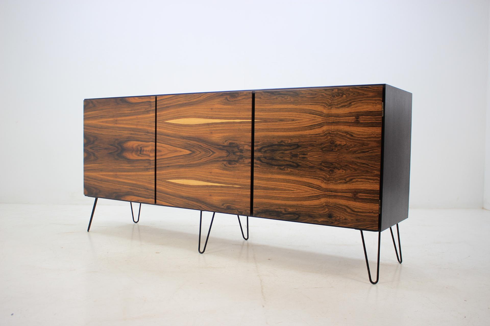 This sideboard features three doors, three shelves and two inner drawers. Black lacquered body with 22% matt lacq. The hairpin iron legs were added afterwards.