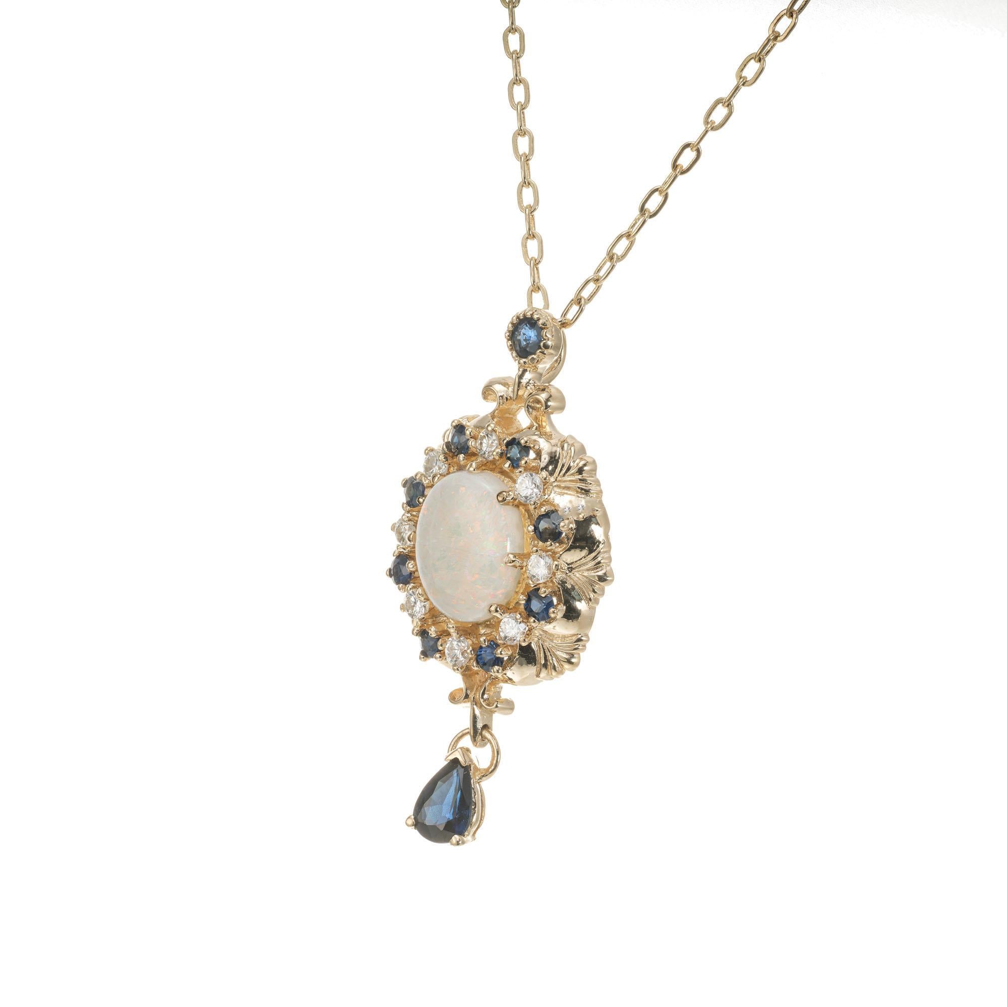 Mid-Century 1960's opal pendant necklace. Oval opal center stone set in 14k yellow gold pendant accented with 9 round sapphires and 8 round brilliant cut diamonds. 1 pear shaped dangle sapphire. 14k yellow gold 16 inch chain.  

1 oval greenish