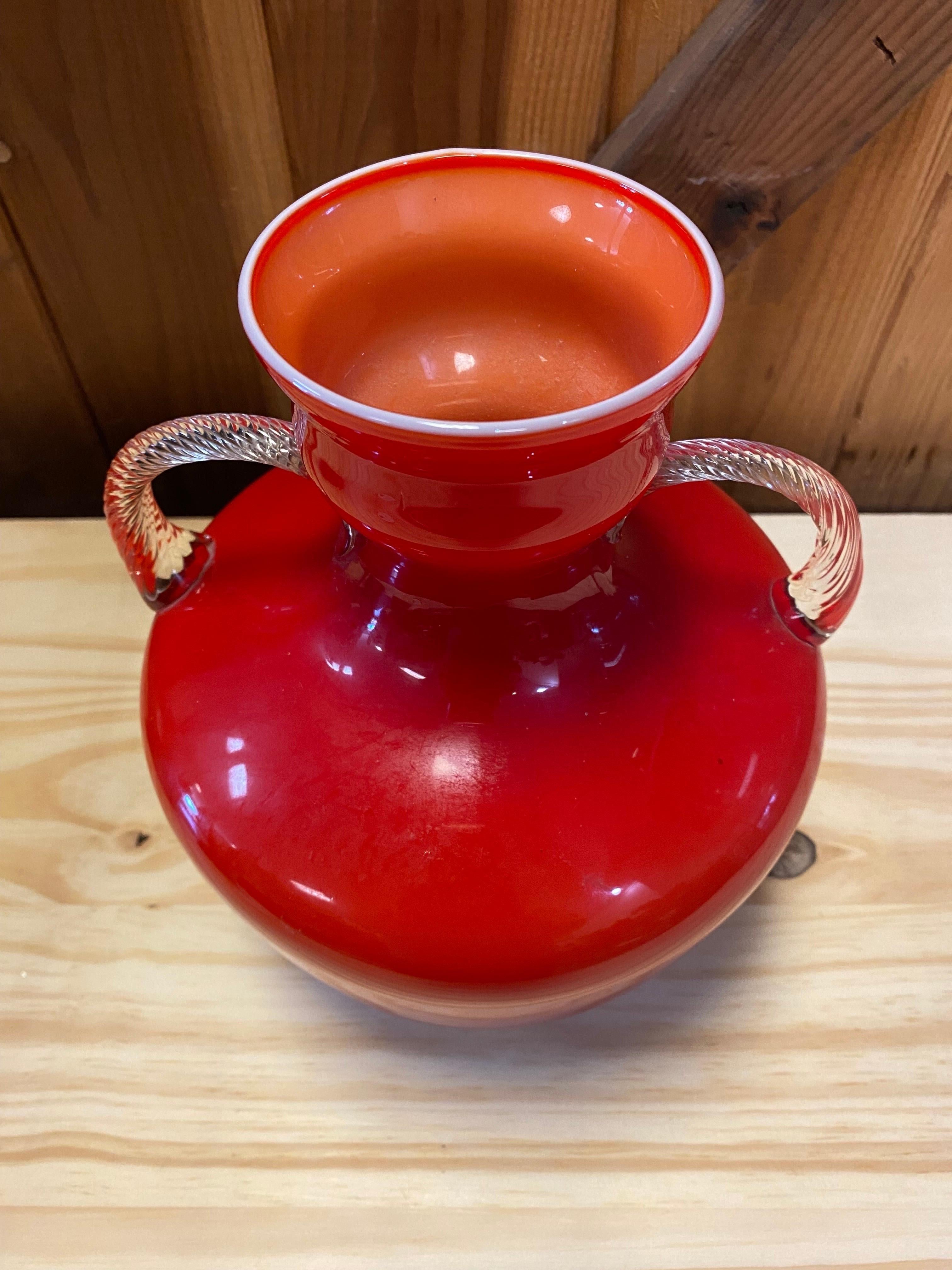 Schöne italienische Vintage-Glasvase mit verschnörkelten, klaren Henkeln. Diese rote Opalina Fiorentina, oder Opaline Florence, Glasvase ist ein echter Hingucker und in ausgezeichnetem Zustand. Siehe Bilder für Details.

Opalina Fiorentina ist eine