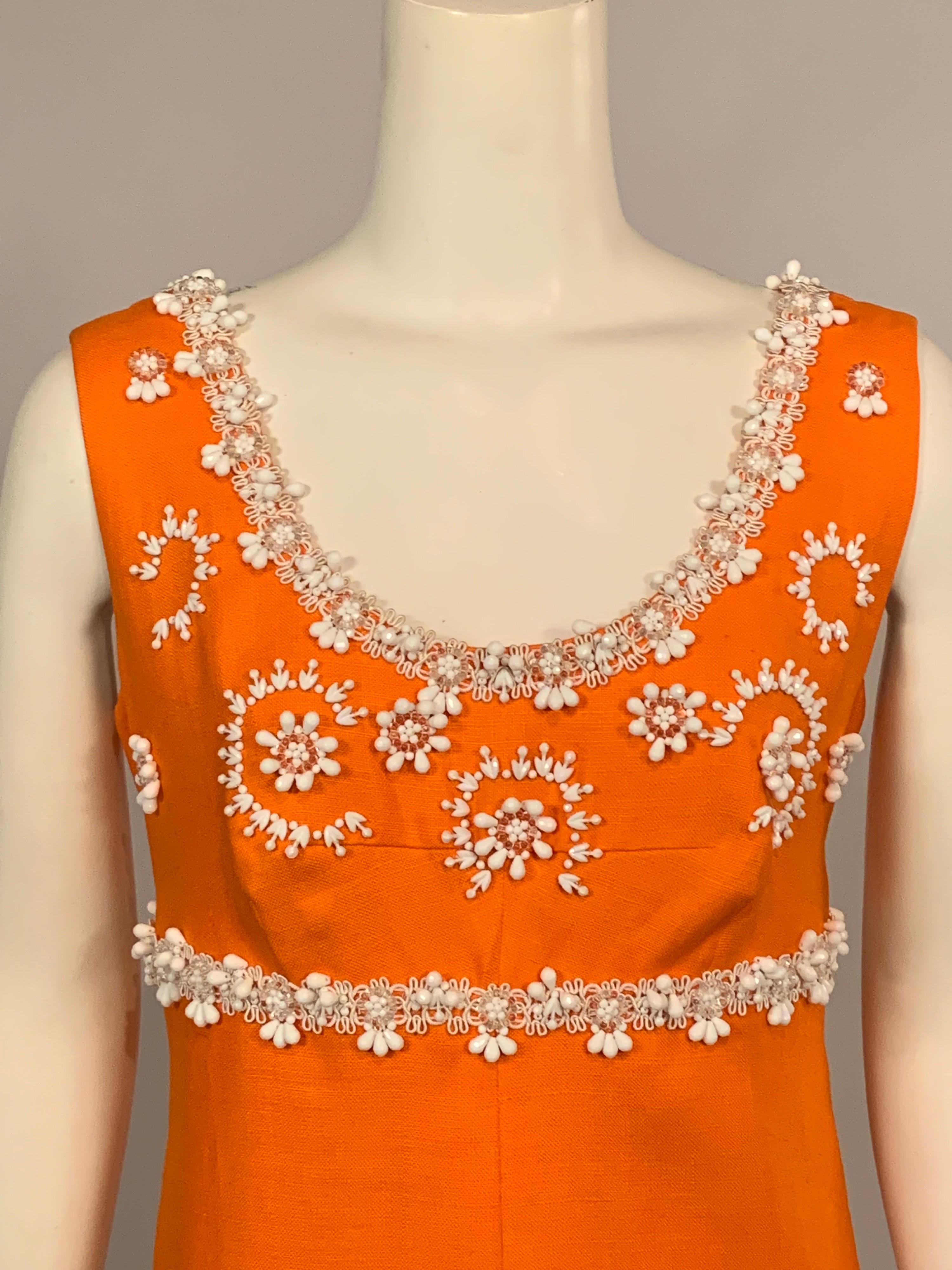 A cheerful bright orange linen dress is embellished with white passementerie and white beadwork on the bodice, empire waistline and the skirt.  It is fully lined and has a center back zipper.
Measurements;   Bust 38