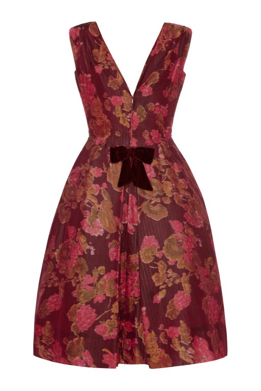 This fabulous 1960s party dress by Elizabeth Arden is likely to have been designed by Oscar de la Renta whilst he was the Head Designer in 1961-63. The dress is made from deep plum coloured silk taffeta with a softly abstracted cerise pink/moss