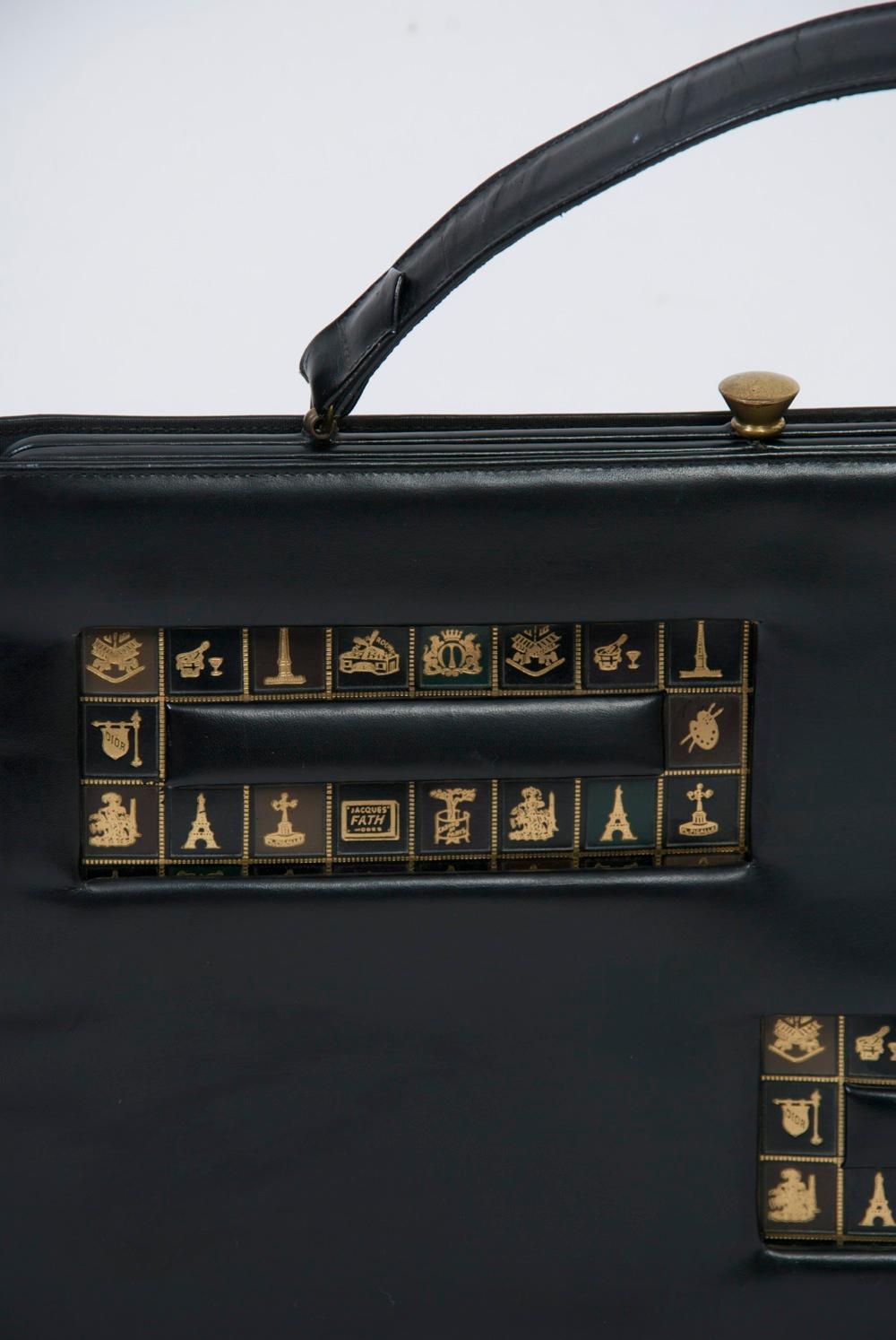 An example of some of the unique large handbags produced in the 1960s, this black leather bag is of rectangular shape and features two offset horizontal sections on the front stamped with gold motifs of Paris, including the Eiffel Tower and two of