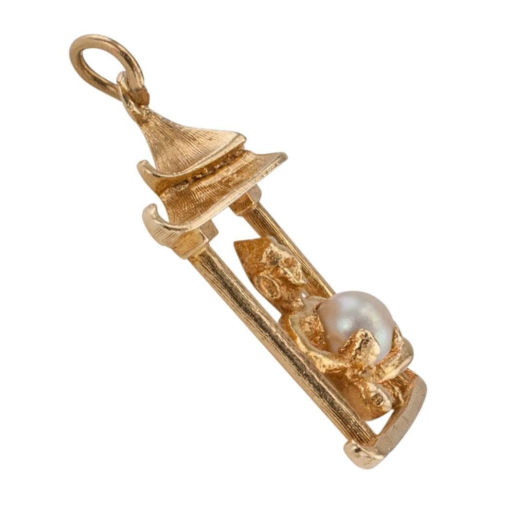 1960s pagoda pearl and gold charm pendant. The open work design styled as a pagoda with a seated deity holding a single cultured pearl, crafted in 14-karat yellow gold. Make someone in your life happy with this vintage pagoda charm as a token of