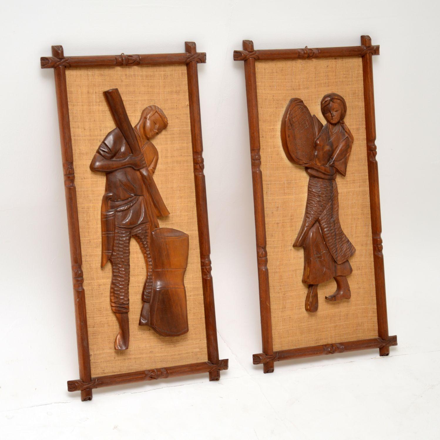 A stunning and unusual pair of vintage reliefs depicting field workers, dating from the 1960s. They are carved from what looks like solid walnut, with carved walnut frames and a rattan background. The condition is excellent for their age, with no