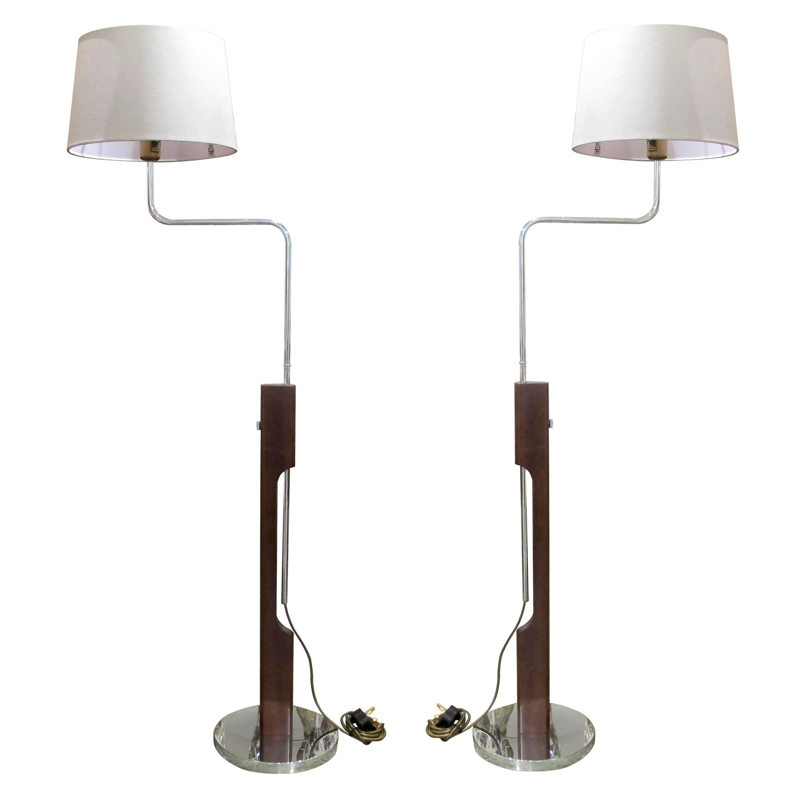 This pair of Swedish floor lamps embodies mid-century modern design's clean lines and functional elegance. Crafted in the 1960s, each lamp features a sleek combination of polished chrome and rich walnut. The slender walnut uprights rise from