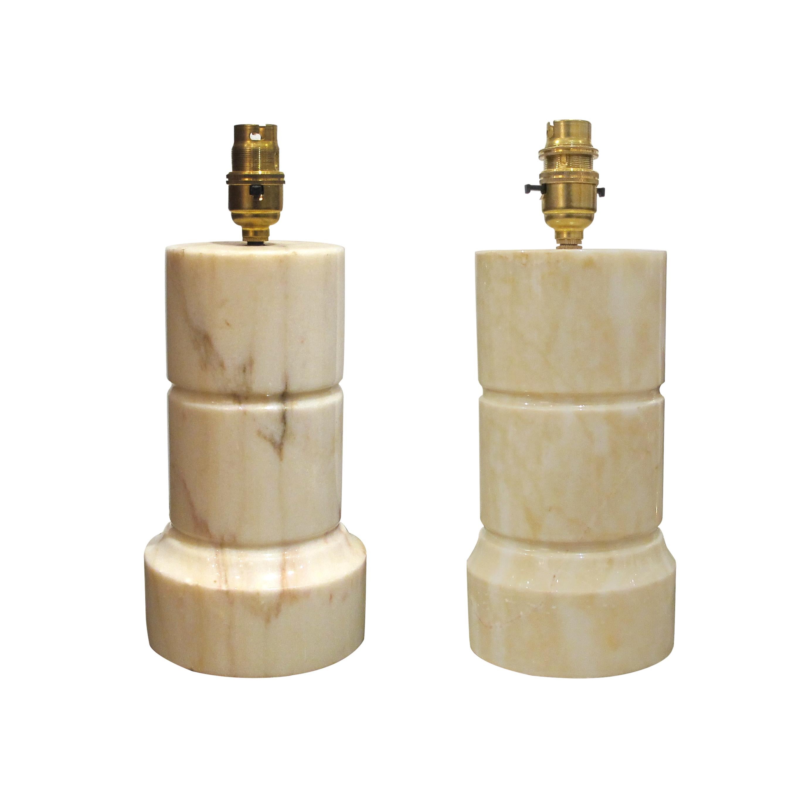 This elegant pair of table lamps is a perfect example of Italian design from the 1960s. The cream marble bases are cylindrical and have a smooth, polished finish. The pair of lamps are complimented with soft pink linen lampshades. The lamps are