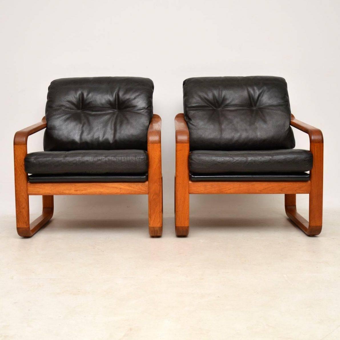 A stunning pair of vintage armchairs in solid teak, with black leather cushions. These were made in Denmark, they date from around the 1960s-1970s. The quality is amazing, they are extremely comfortable, and the condition is superb for their age.