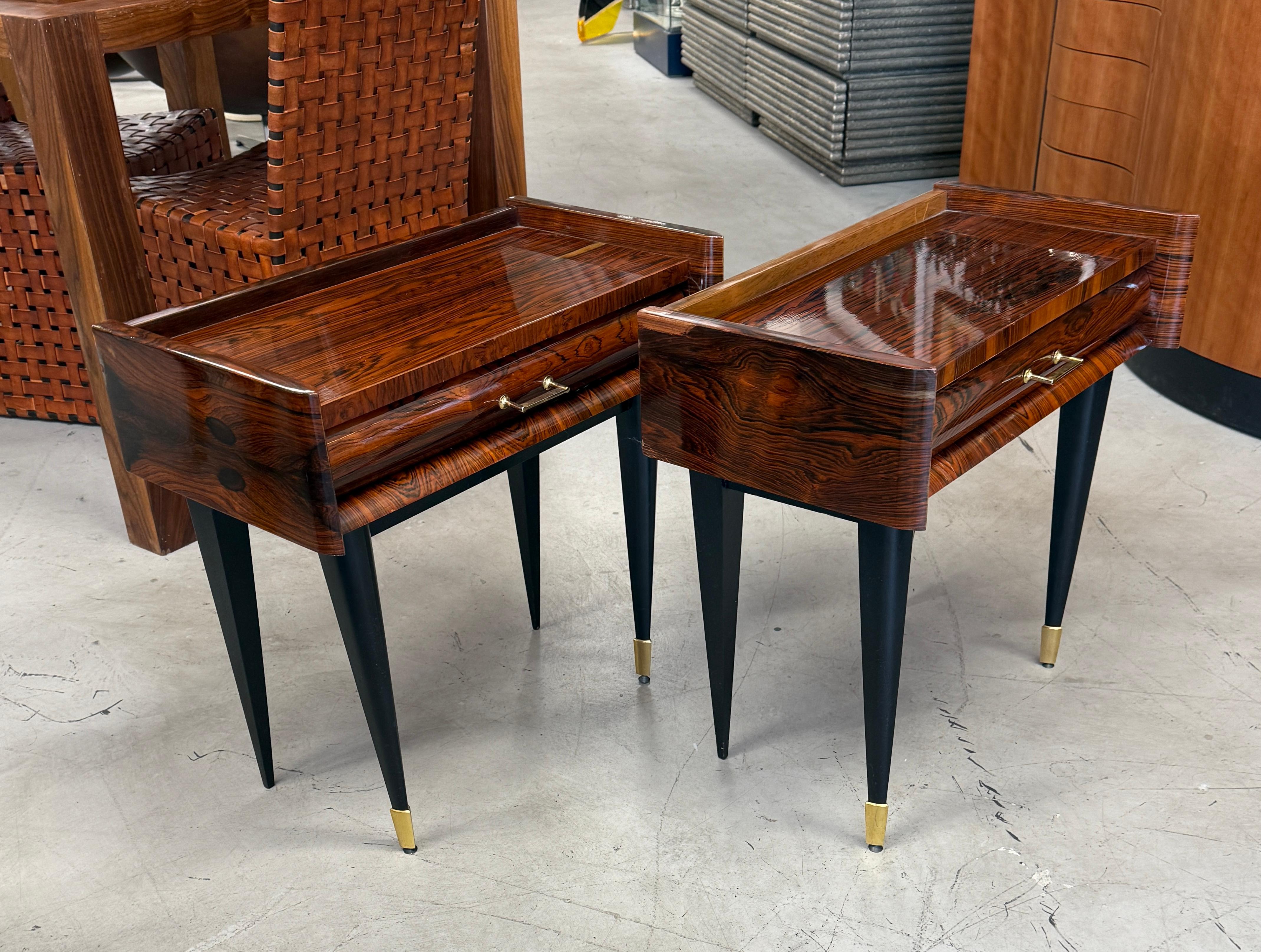 Un precioso par de elegantes mesillas de noche de palisandro veteado bellamente chapado. Cada soporte tiene un cajón. Probablemente datan de la década de 1960. Cada uno tiene una pegatina en el interior del cajón que dice NF Ameublement. 
Las patas