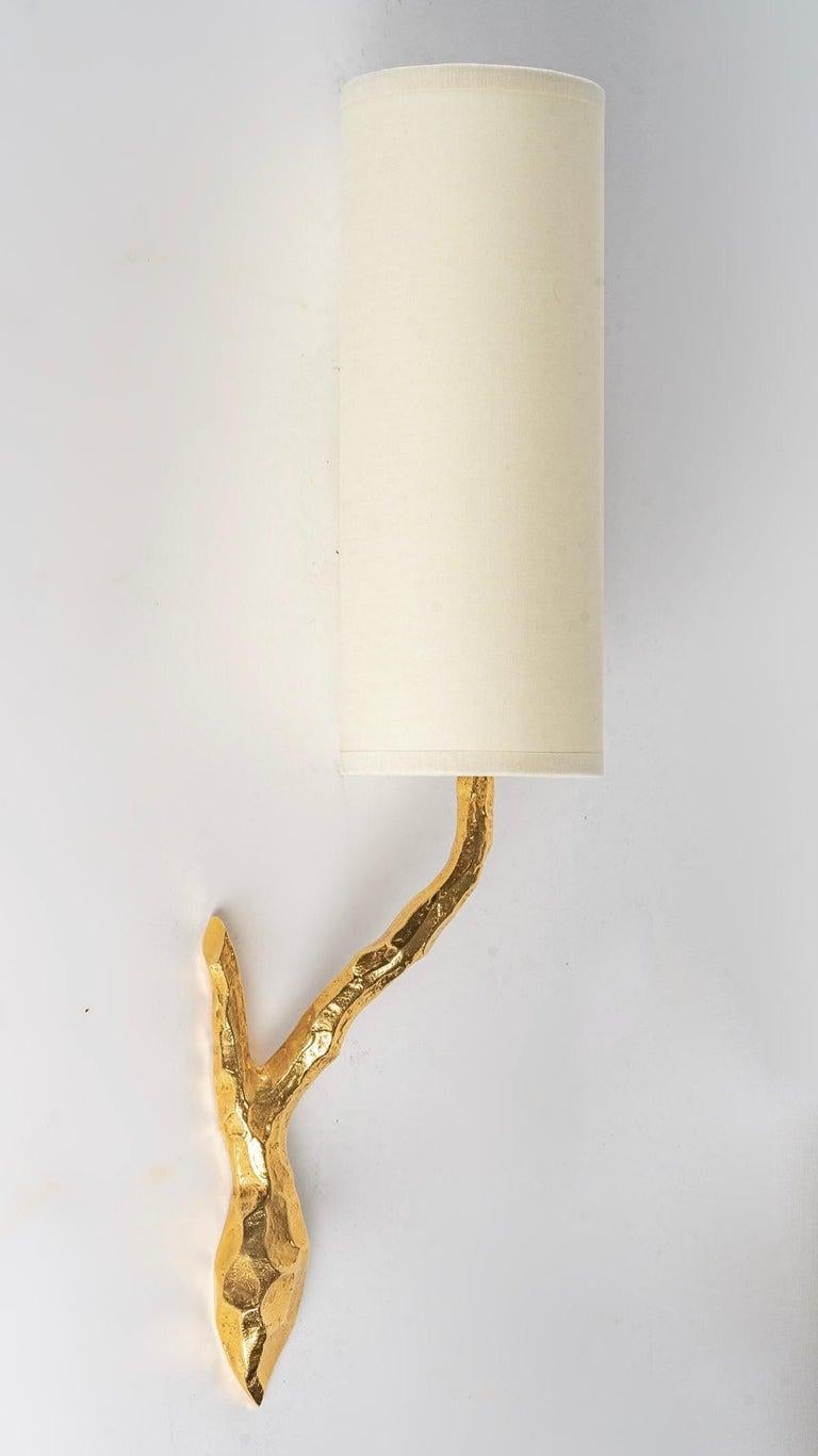 Elegant ormolu sconces designed by Maison Arlus in the 1960s. 
Each arm represents a stylized branch in gilt bronze, they respond to each other.
The lampshades are cylindrical and made of off-white cotton.

One bulb per lamp.