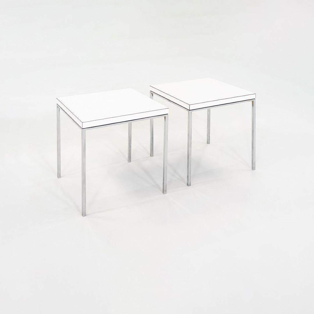 This is a pair of square side tables, designed by Davis Allen under the leadership of Gordon Bunshaft within SOM. The sophisticated design features a highly polished stainless-steel base and has a white laminate square top that sits flush with the