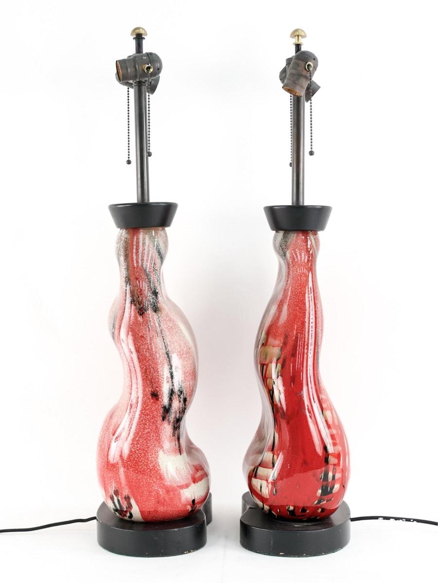 1960s pair of Italian ceramic studio lamps. The lamps have vibrant colors, black lacquered base and tops with brass finials.