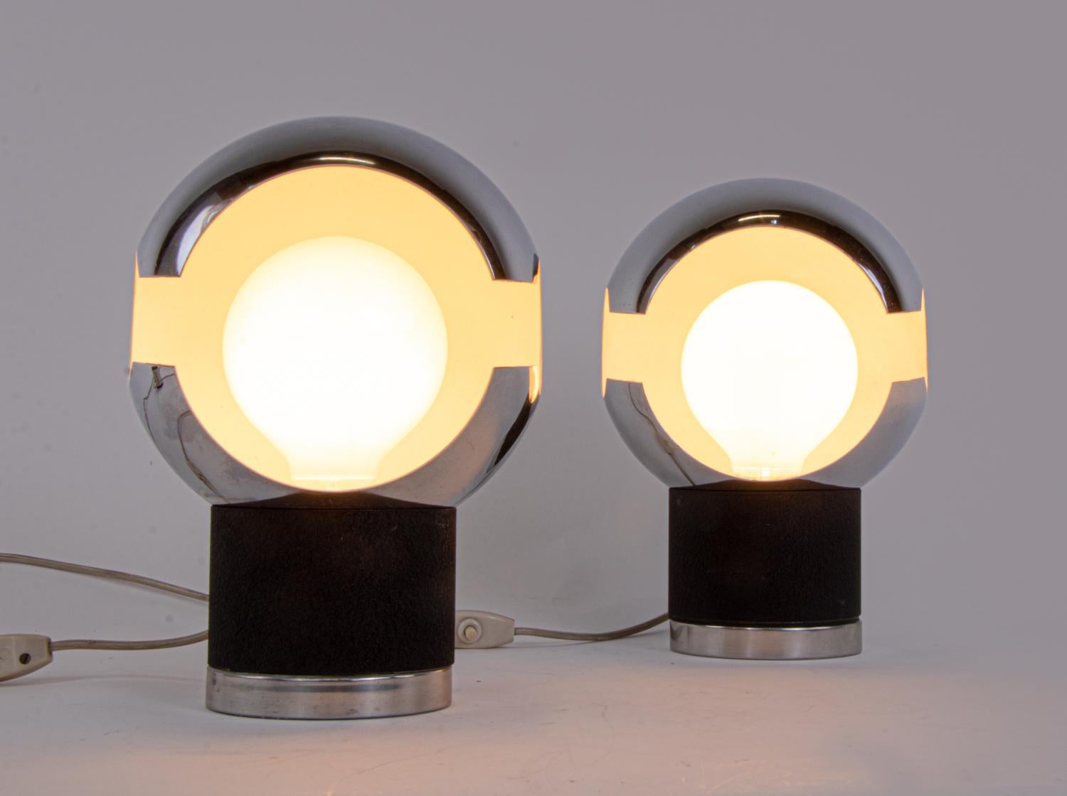 These exceptional table lamps are made of chromed globe shades and black shrink lacquered metal bases. 
Made in Italy in the 1960s. 
When the lights are on, they look spectacular. Gem from the time.

Measures: 6.7