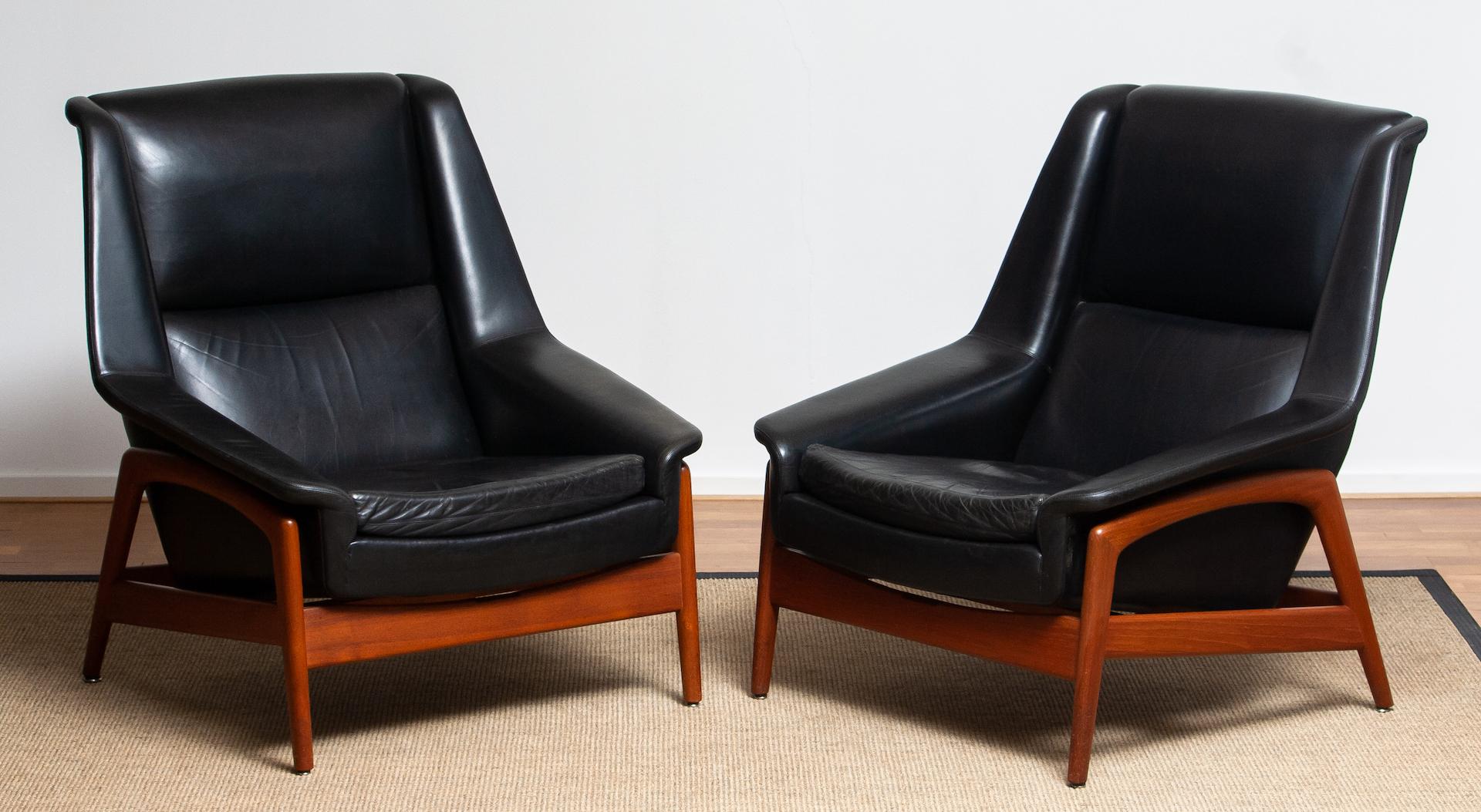 Stunning set of two easy or lounge chair in teak and upholstered with black leather by Folke Ohlsson for DUX, Sweden, model: Profil overall in good and both in original condition. Note the there is one head cushion.