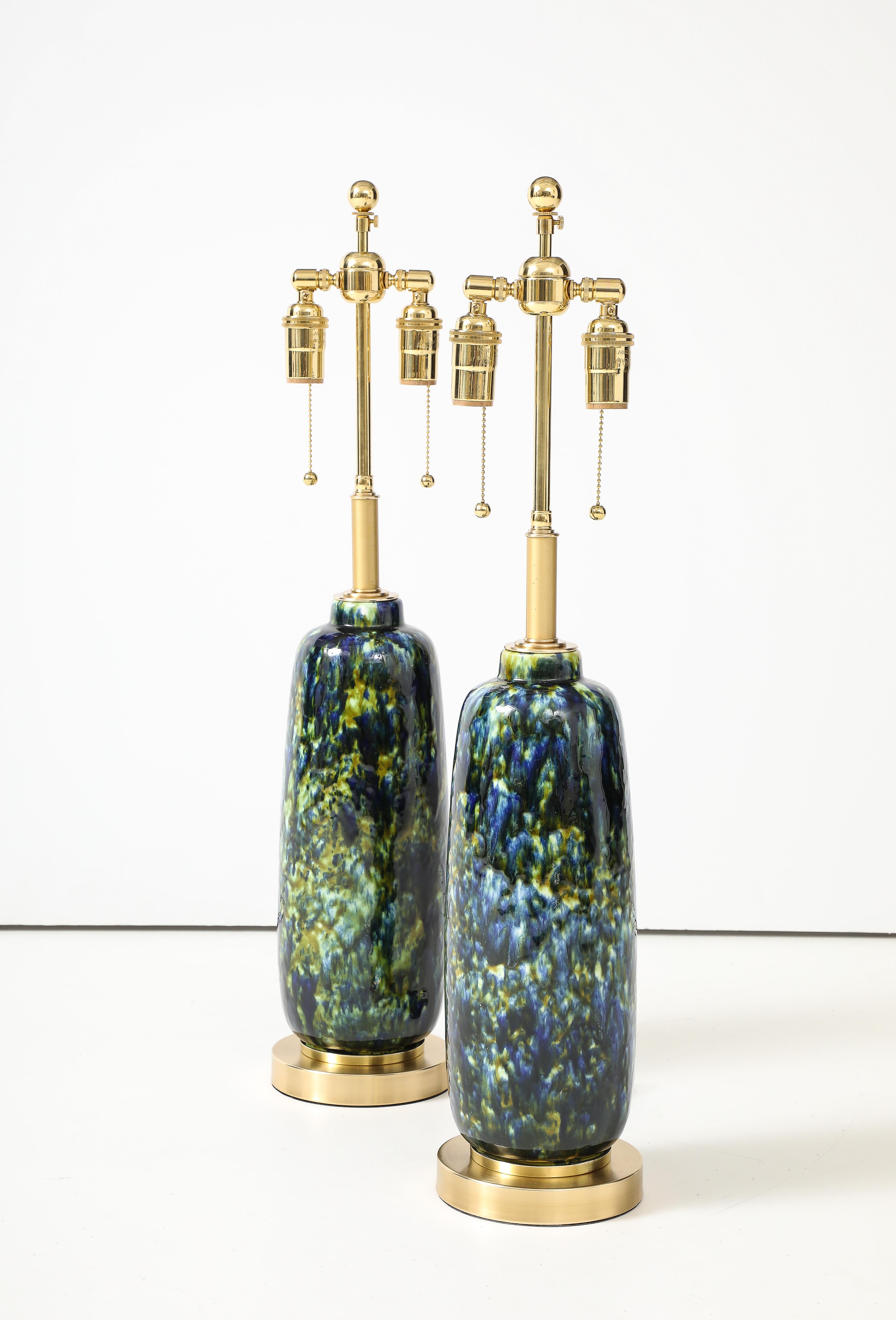 1960's Pair of Mid-Century ceramic lamps with a  beautiful peacock color glaze.
The lamps sit on polished brass bases and they have been Newly rewired with
adjustable polished brass double clusters that take standard size light bulbs.
Each socket