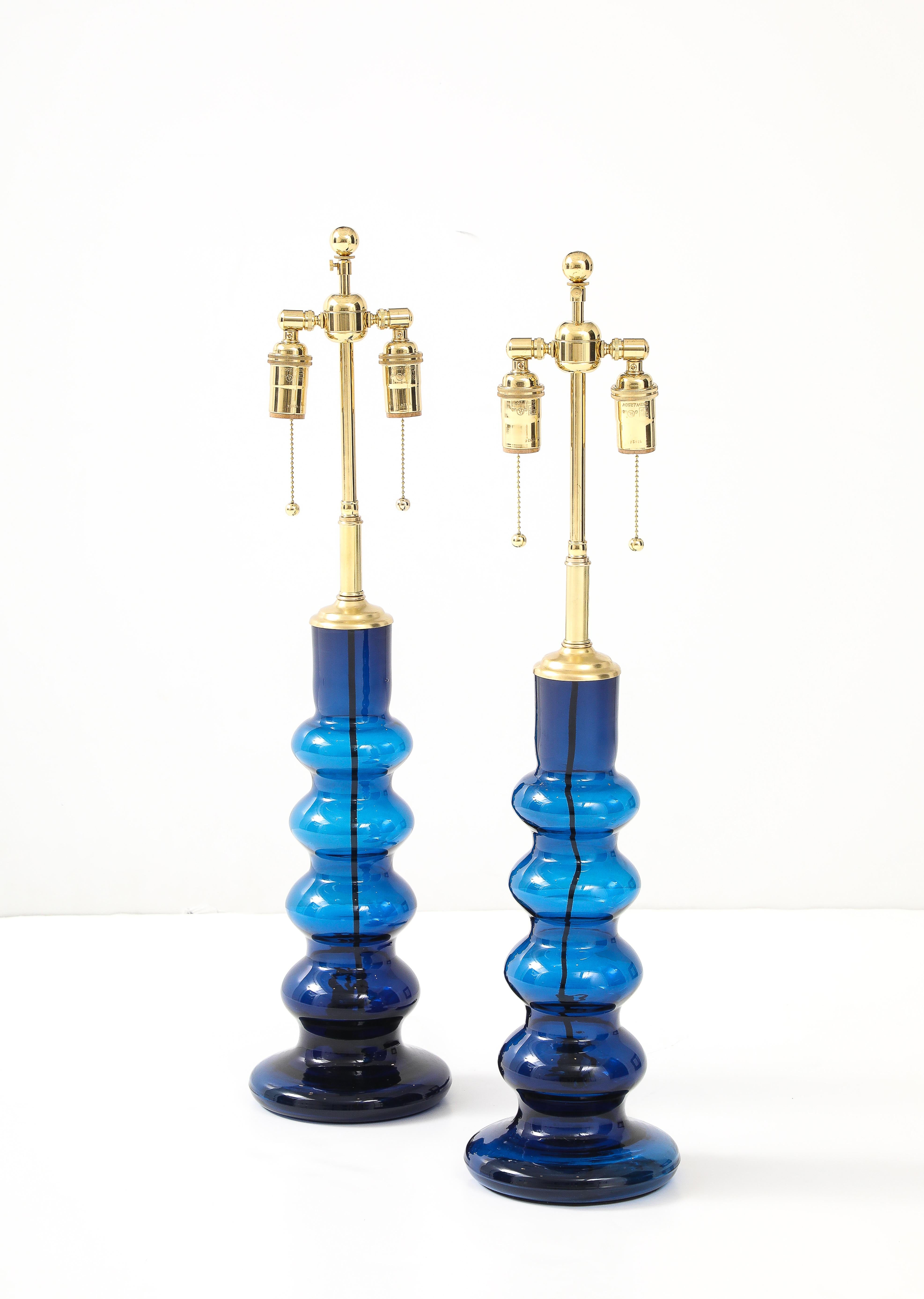 Pareja de 1960  Lámparas Totem suecas de cristal azul.
Las lámparas se han recableado de nuevo para EE.UU. con racimos dobles ajustables de latón pulido 
y cordones de rayón de seda.
Cada casquillo admite hasta 60 vatios / 12 vatios por lámpara y