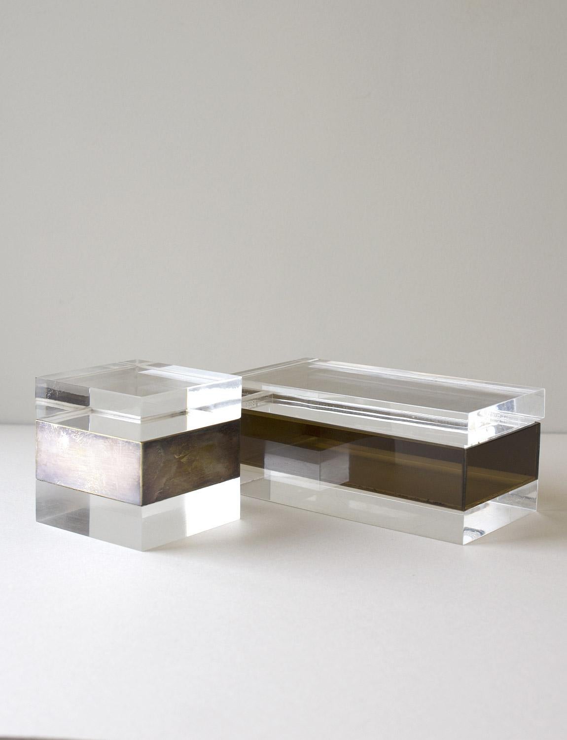 Two Italian 1960s/70s plexiglass ornament boxes. The rectangular box has a thick perspex brown brand and the cube shaped box has a metal band. The pair look extremely chic on a desk or coffee table.

Dimensions: Rectangular box H8cm X W21cm X D11cm,