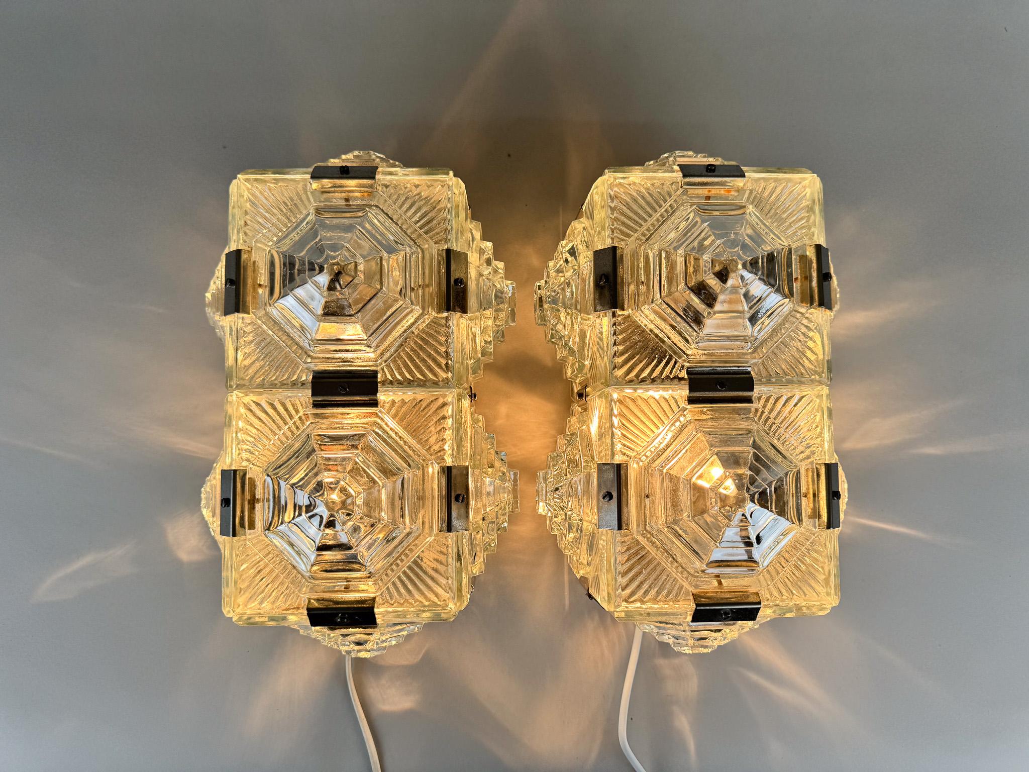 Ensemble de deux appliques murales vintage en verre pressé et raccords chromés. Produit par Kamenicky Senov Glasswork dans l'ancienne Tchécoslovaquie dans les années 1960. 
Ampoules : 2 x E26 (E27). Recâblé. Compatible avec le câblage américain.
