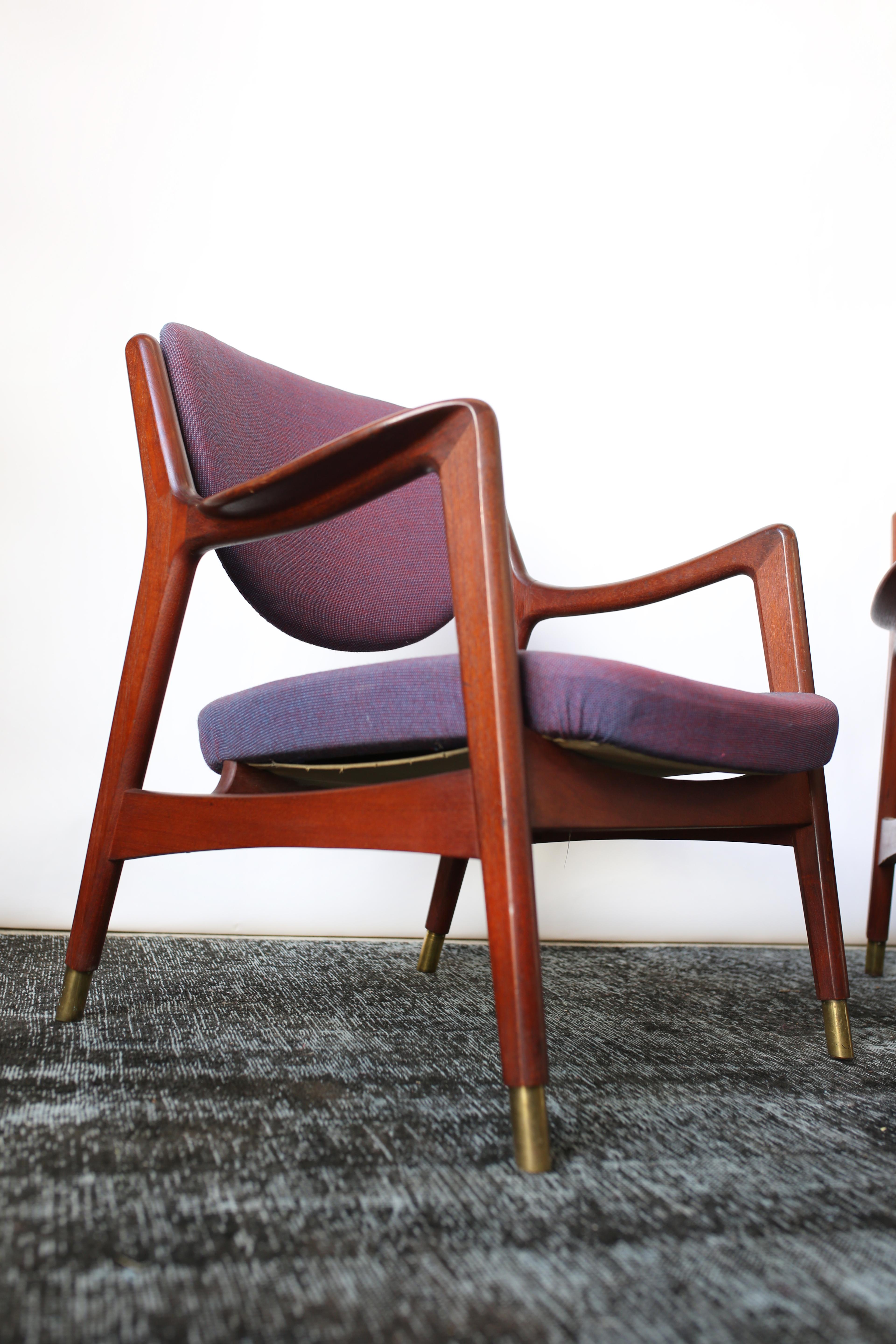 This pair of Norwegian sculptural teak lounge chairs are in overall good condition and wear consistent with age and use.  Original purple/red upholstery, with several tiny holes. (Shown in photos).  Solid teak frame with brass caps. Designer/Maker