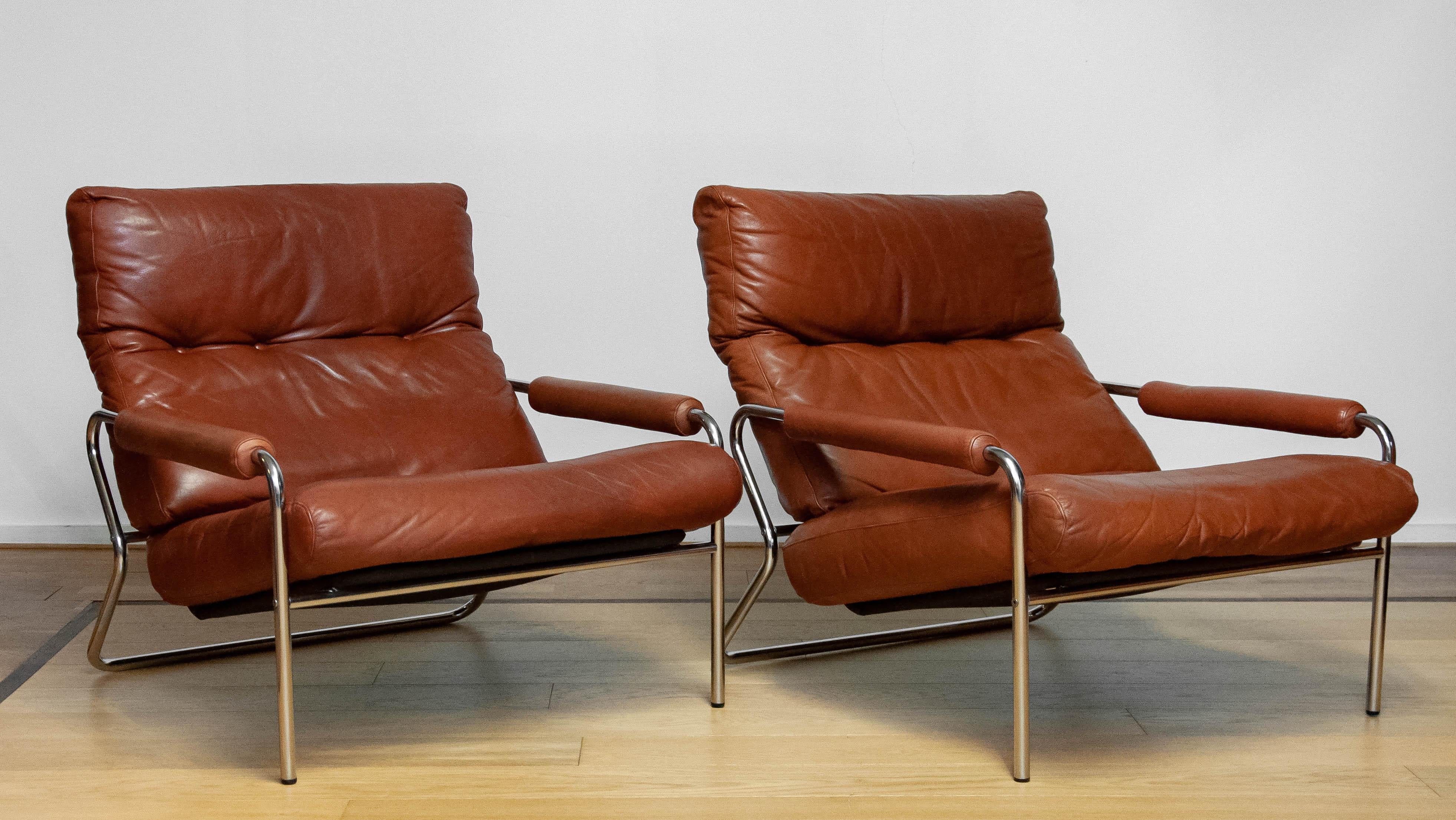Beautiful pair Scandinavian Modern tubular lounge chairs with brown leather cushions and brown leather armrests from the 1960s made in Sweden.
The leather is for both chairs in good condition even as the fillings and therefor both chair are very