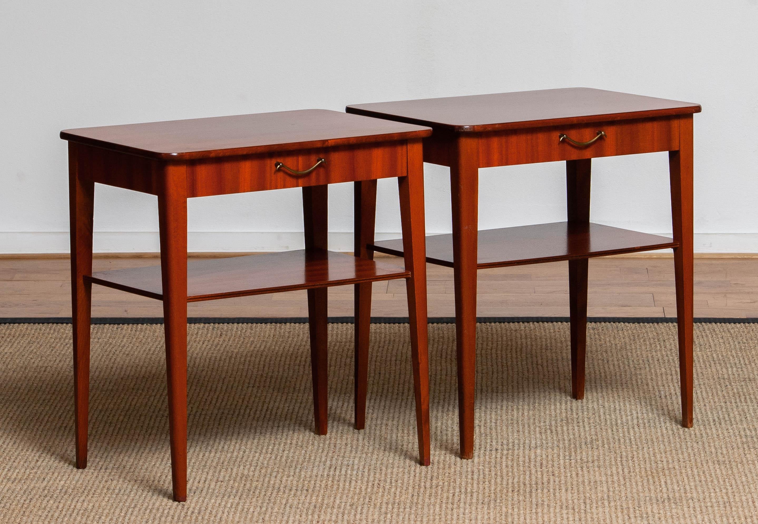 Set of two slim Swedish bedside tables / night stands in mahogany both with a drawer and a shelf. 
Made in the 1960's and in overall good condition.