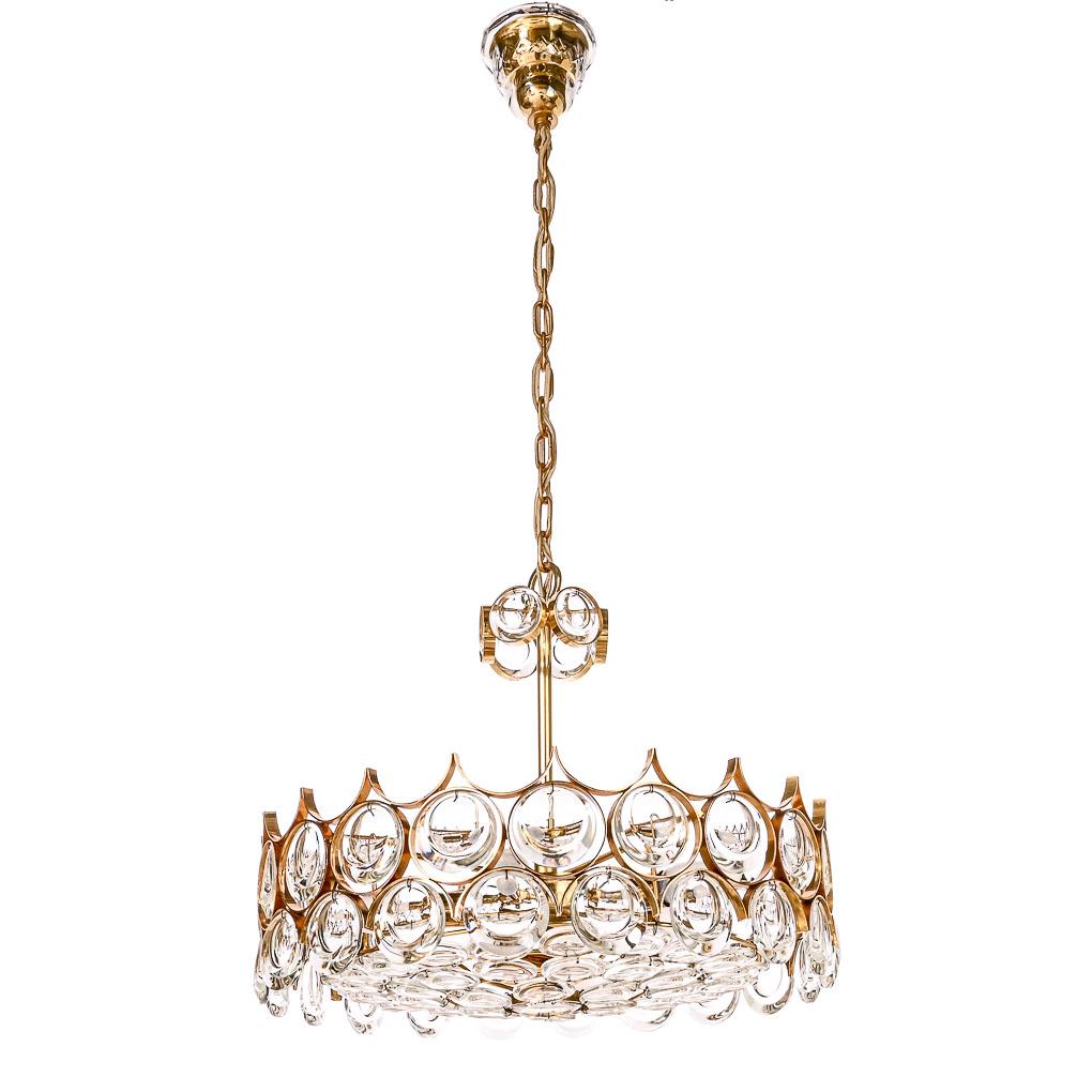 Elegant chandelier with jewel-like crystal glass and gilt brass rings by Palwa. 40 large round crystal glass ornaments and 5 small glass ones around the side of the lamp, it has a beautiful decorated glass foot, and plate below has 38 small round