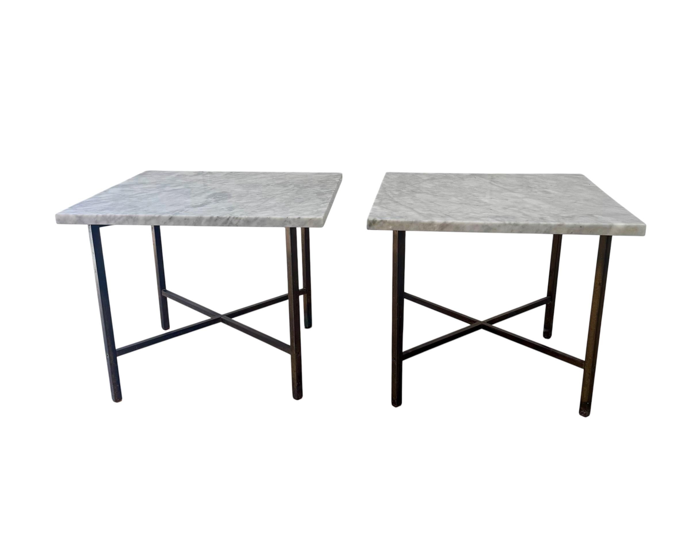 These mid-century modern side tables are in the style of Paul McCobb, featuring sleek square white marble tops with subtle grey veining. The elegant brass X-base frames provide both stability and visual interest, with slender legs that cross at the