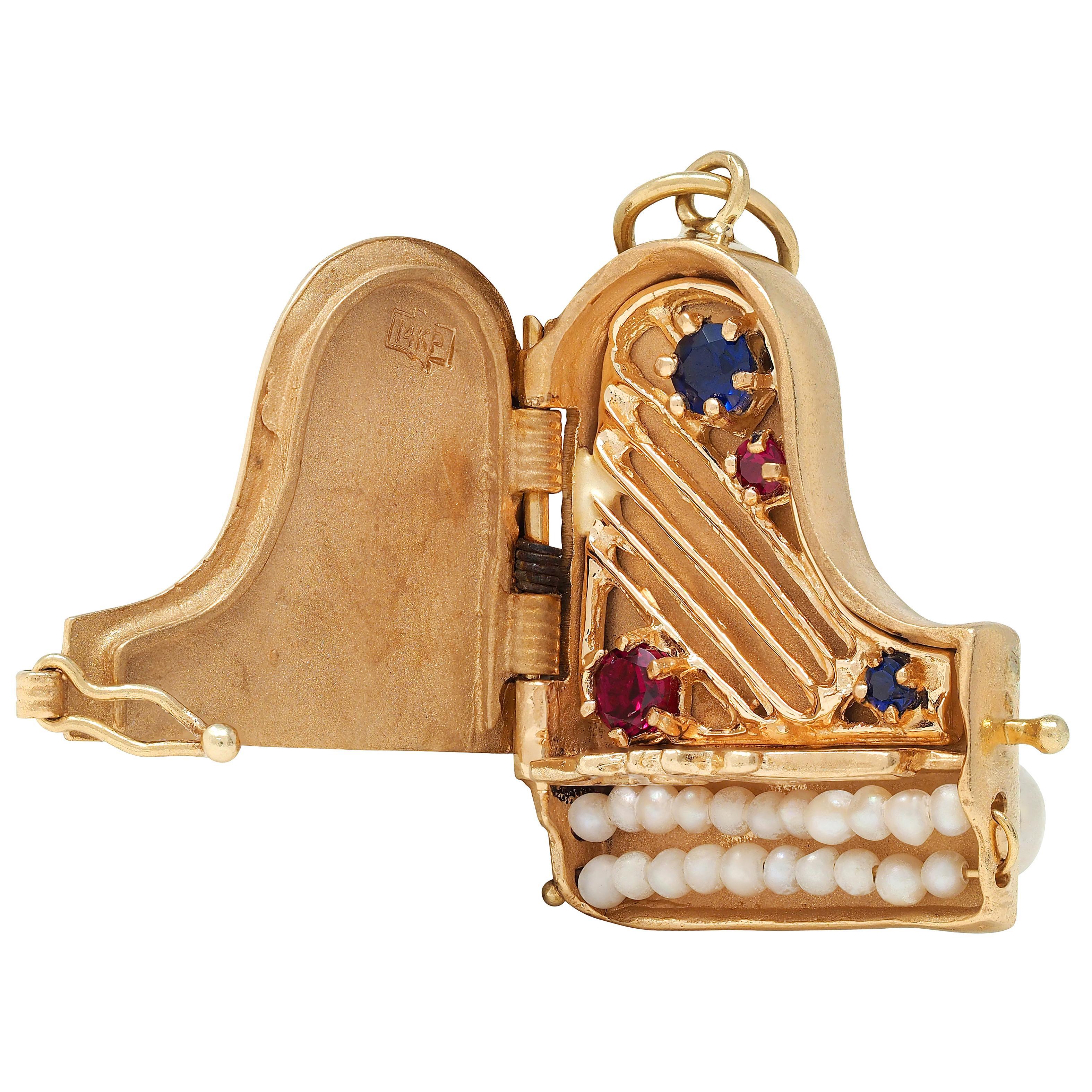 Designed as a highly dimensional grand piano with grooved details and hinged top
Opening to reveal gold strings with prong set round cut sapphires and rubies
With additional sapphires and rubies prong set on top in an alternating row
Transparent