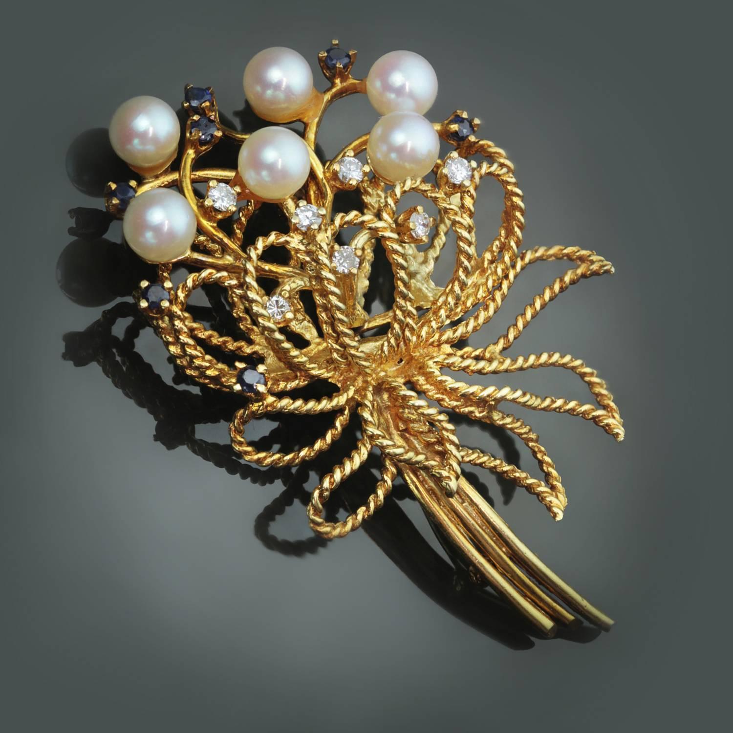 This elegant circa 1963 brooch is made in twisted 18k yellow gold and prong-set with 7 sparkling diamonds, 7 faceted blue sapphires, and 6 6.0mm cultured pearls. Signed Karbra. . 
