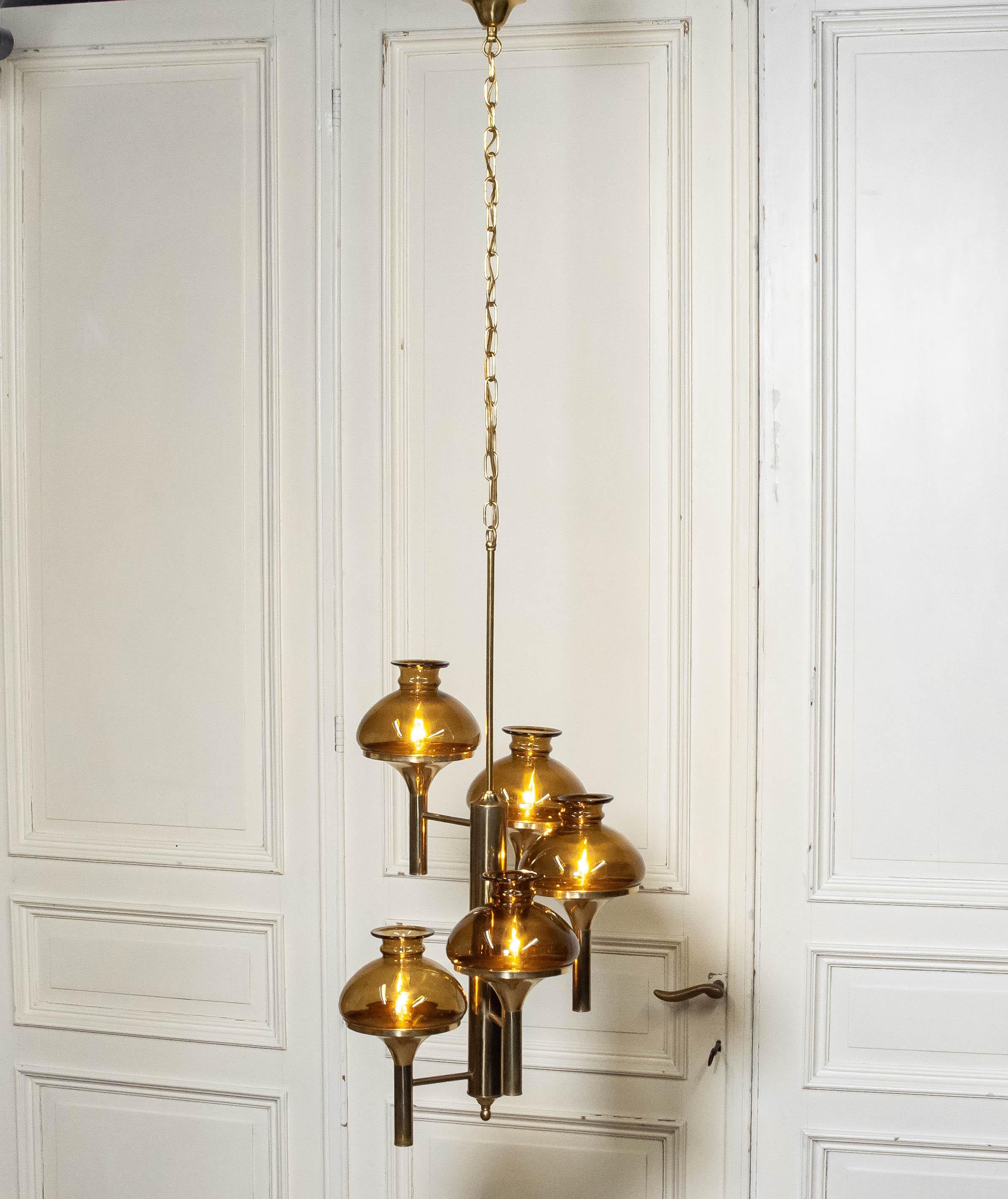 Il s'agit d'une lampe suspendue conçue par Svend Mejlstrøm pour Mejlstrøm Belysning en Norvège dans les années 1960.
Le lustre présente un cadre en laiton remarquable associé à des abat-jours en verre brun chaud, créant un effet de lumière doux et