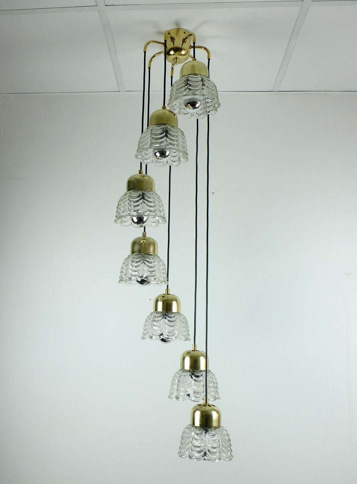 Lampe à suspension italienne autrichienne glamour des années 1960. Il est fabriqué en laiton poli et comporte 7 bras avec des abat-jour en verre en forme de fleur suspendus à différentes longueurs. Les abat-jour sont en verre épais. Fils électriques