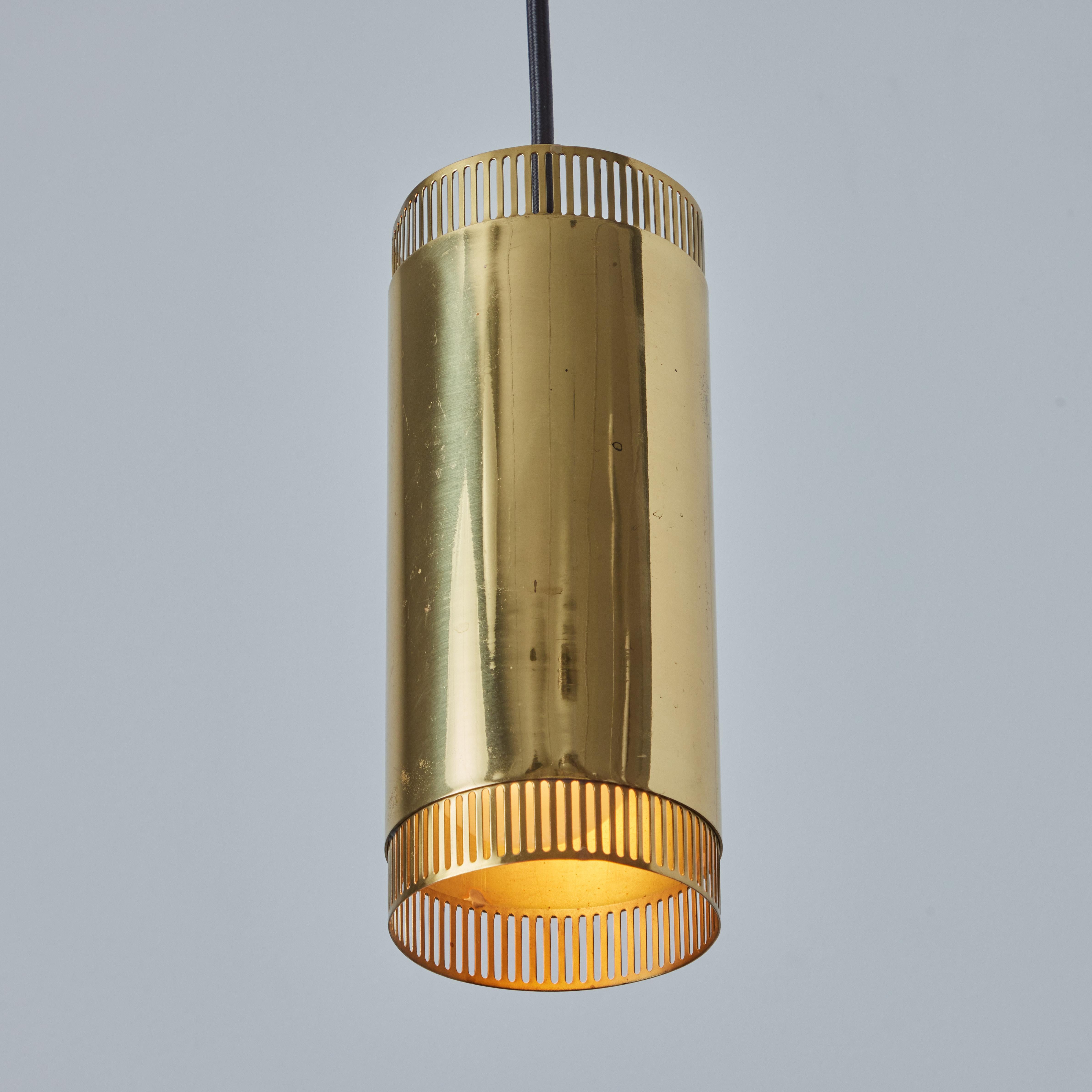 1960s Perforated Brass Cylindrical Pendant Attributed to Mauri Almari for Idman. A quintessential example of Finnish design, these pendants are executed in perforated polished brass and have been professionally modified for mounting over a standard