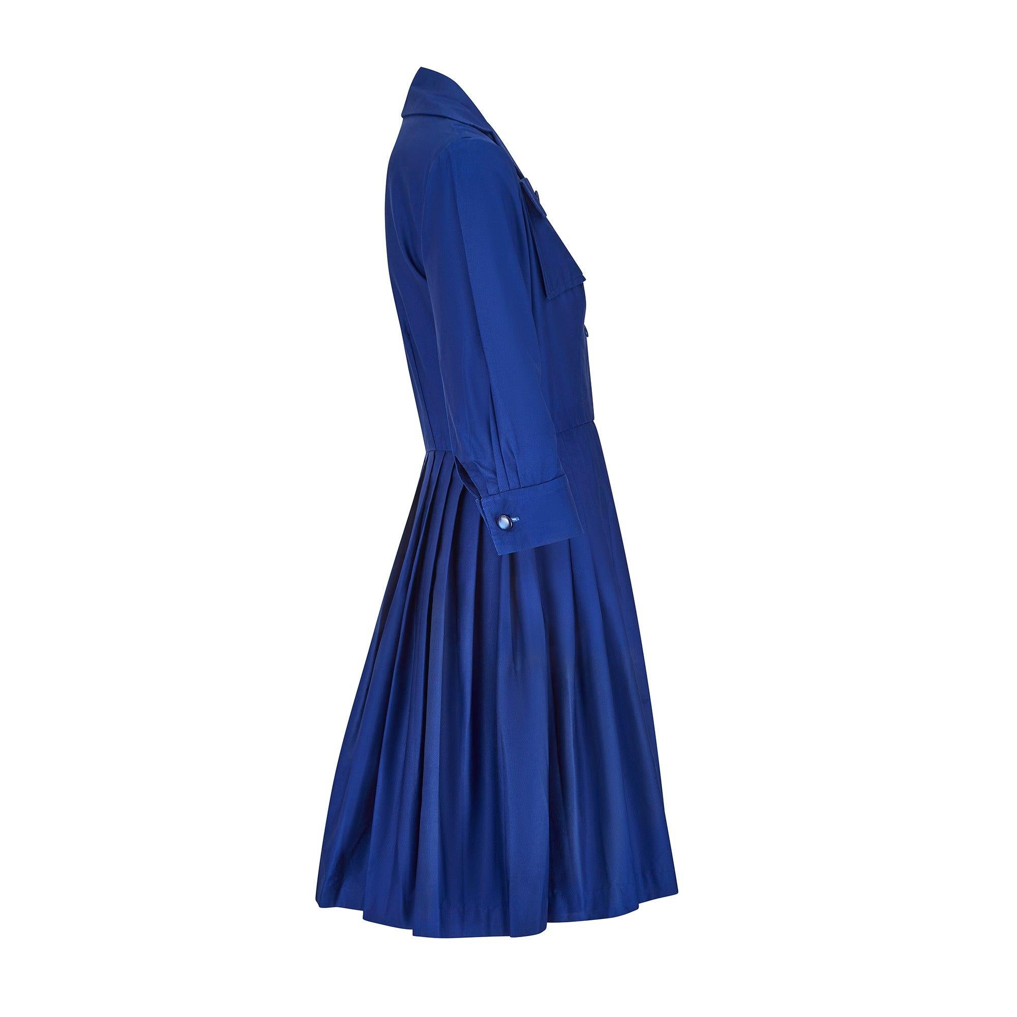 This shirt dress was designed by Peter Barron in London in the 1960s. It has a timeless shirt-dress silhouette with a nipped-in waist and button-down front. Drawing on elements of classic French workwear, it is cut from thick blue cotton, with wide