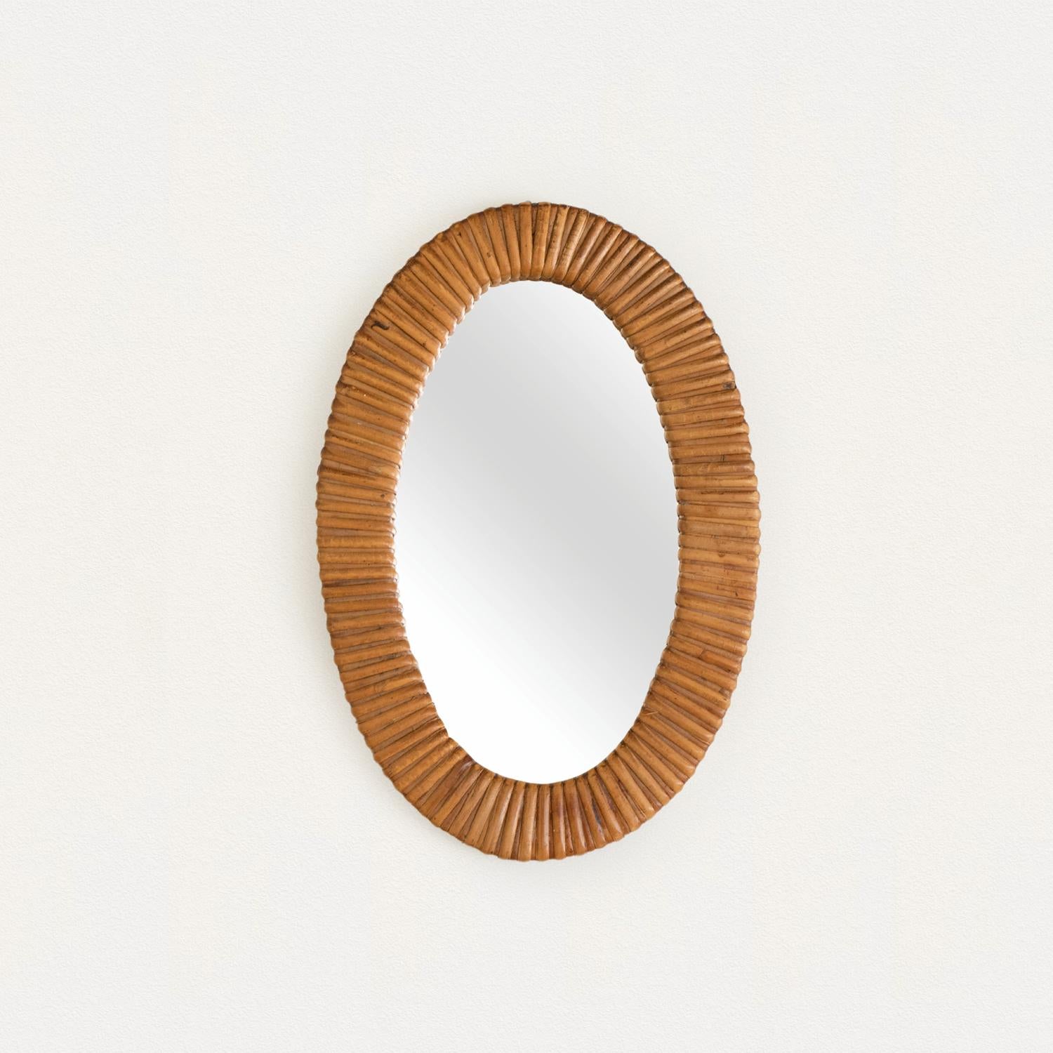 Small size rattan mirror in an oval shape with wrapped rattan encompassing the mirror. Nice vintage condition with original mirror. From France, 1960's.