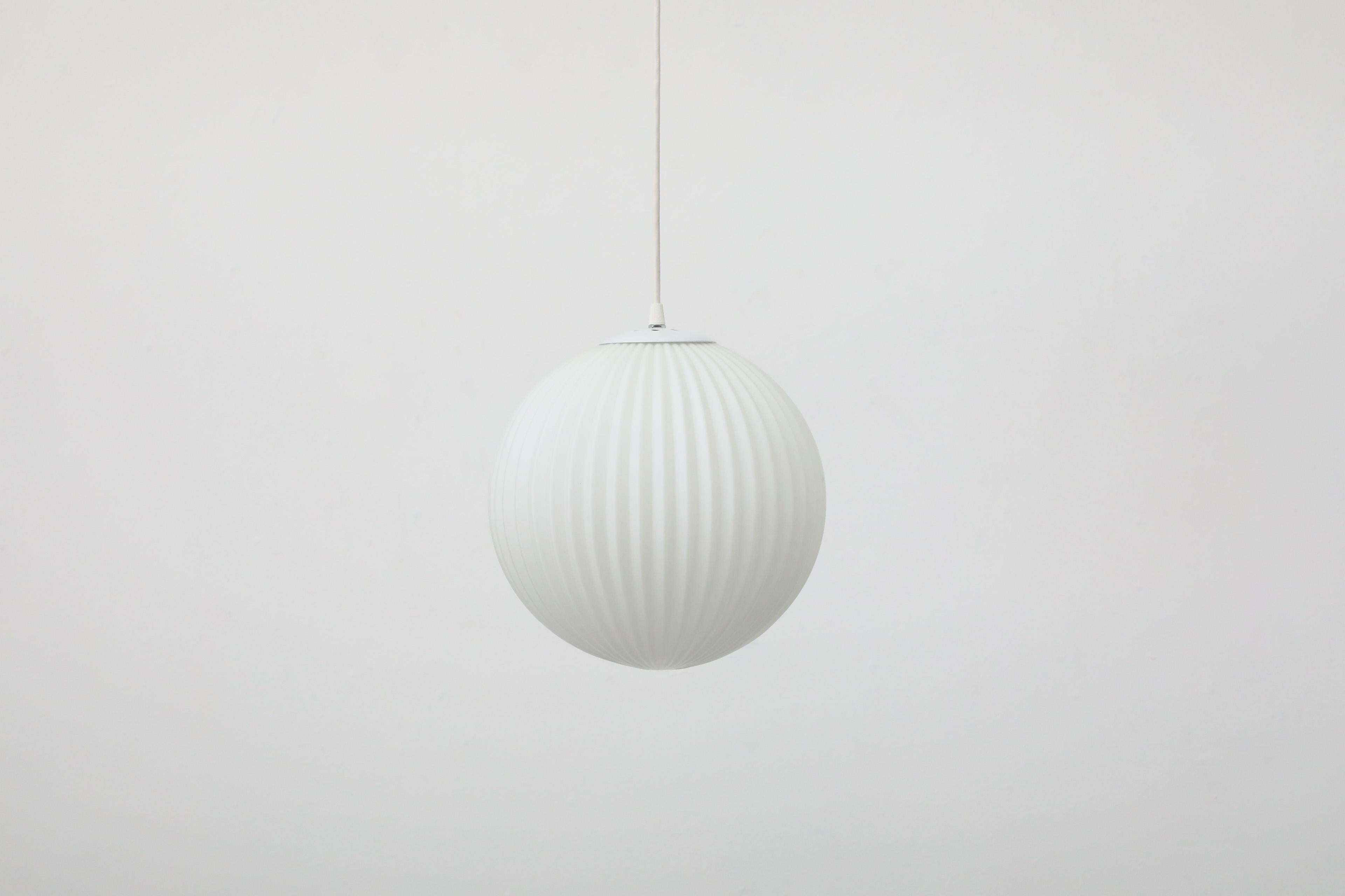 Beautiful 1960s Philips attributed ribbed milk glass globe ceiling pendant with white enameled hardware. In original condition with minimal wear consistent with age and use.